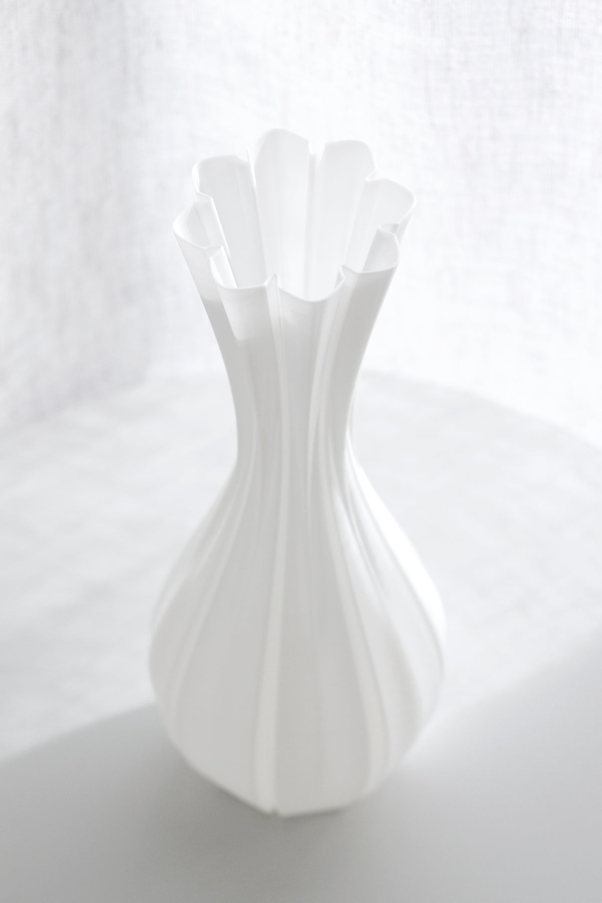 Close view of the fluted vase, its scalloped rim opening above the ribbed body
