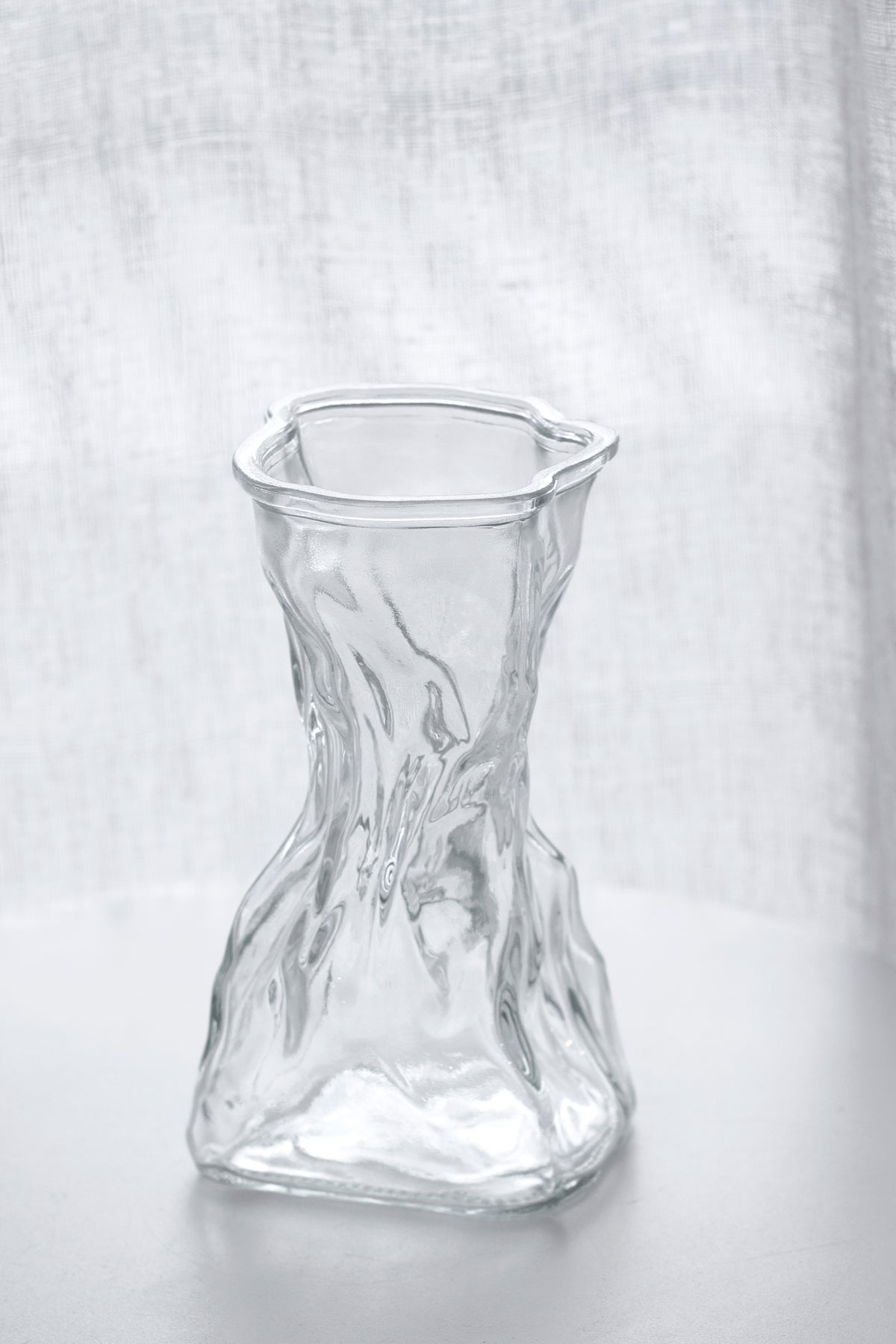 Clear crinkle vase front on against a woven linen backdrop