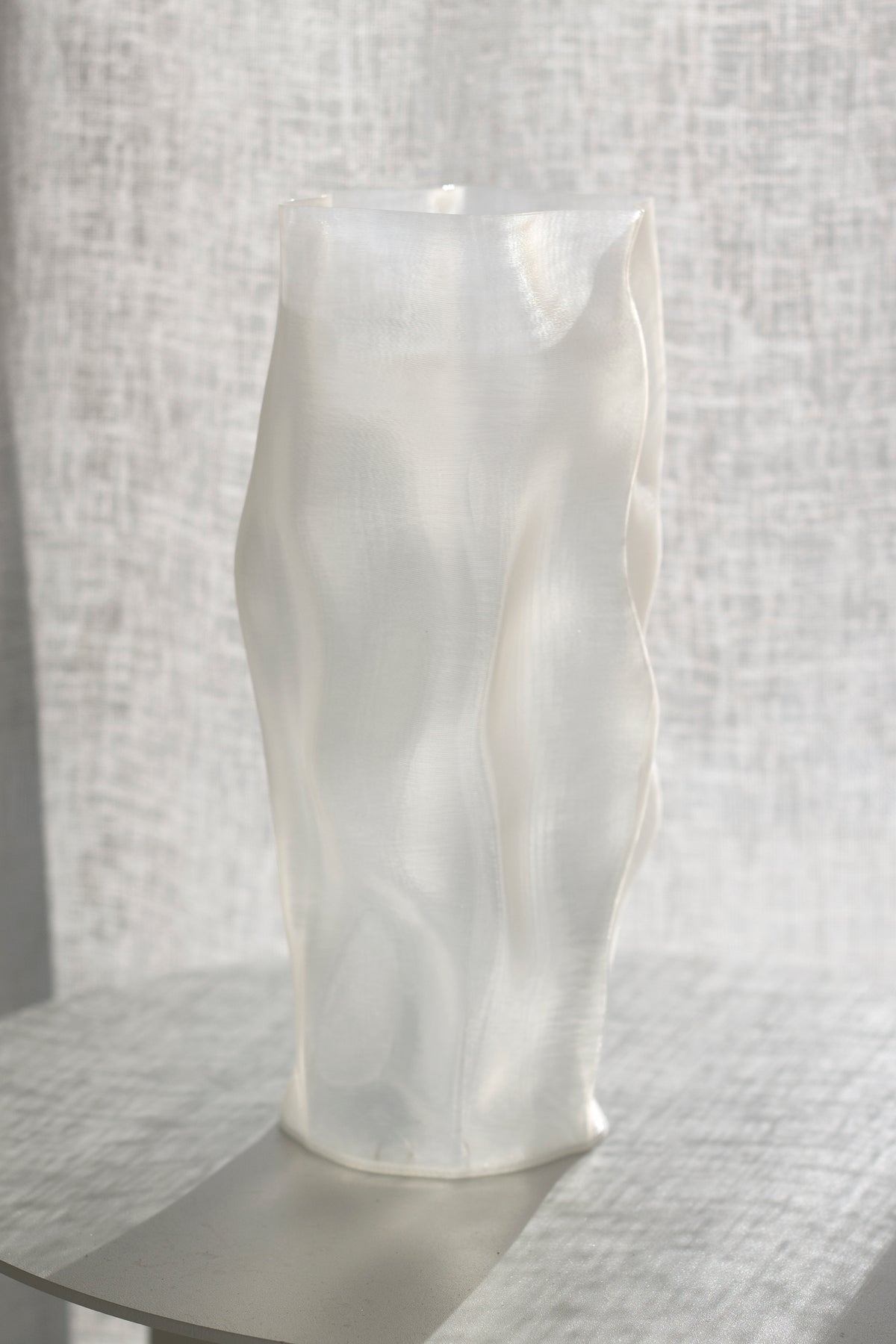 Ripple vase front on atop a grey tabletop, pale linen hanging behind