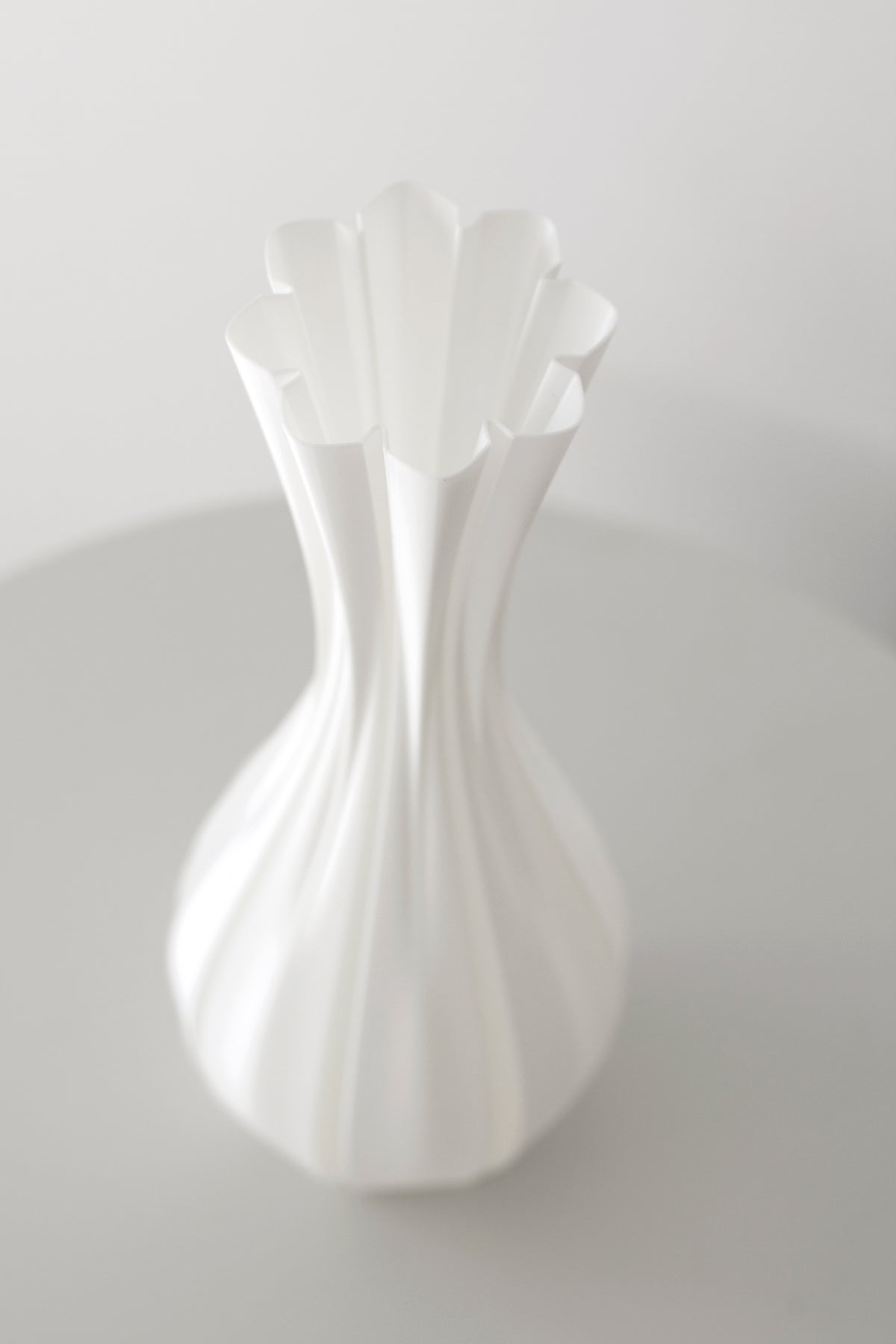 Angled close view of the fluted vase showing the flared scalloped rim above the narrow waist