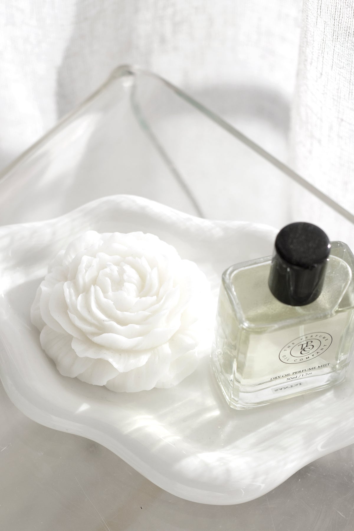 White cloud ceramic tray holding a rose shaped candle and a perfume bottle