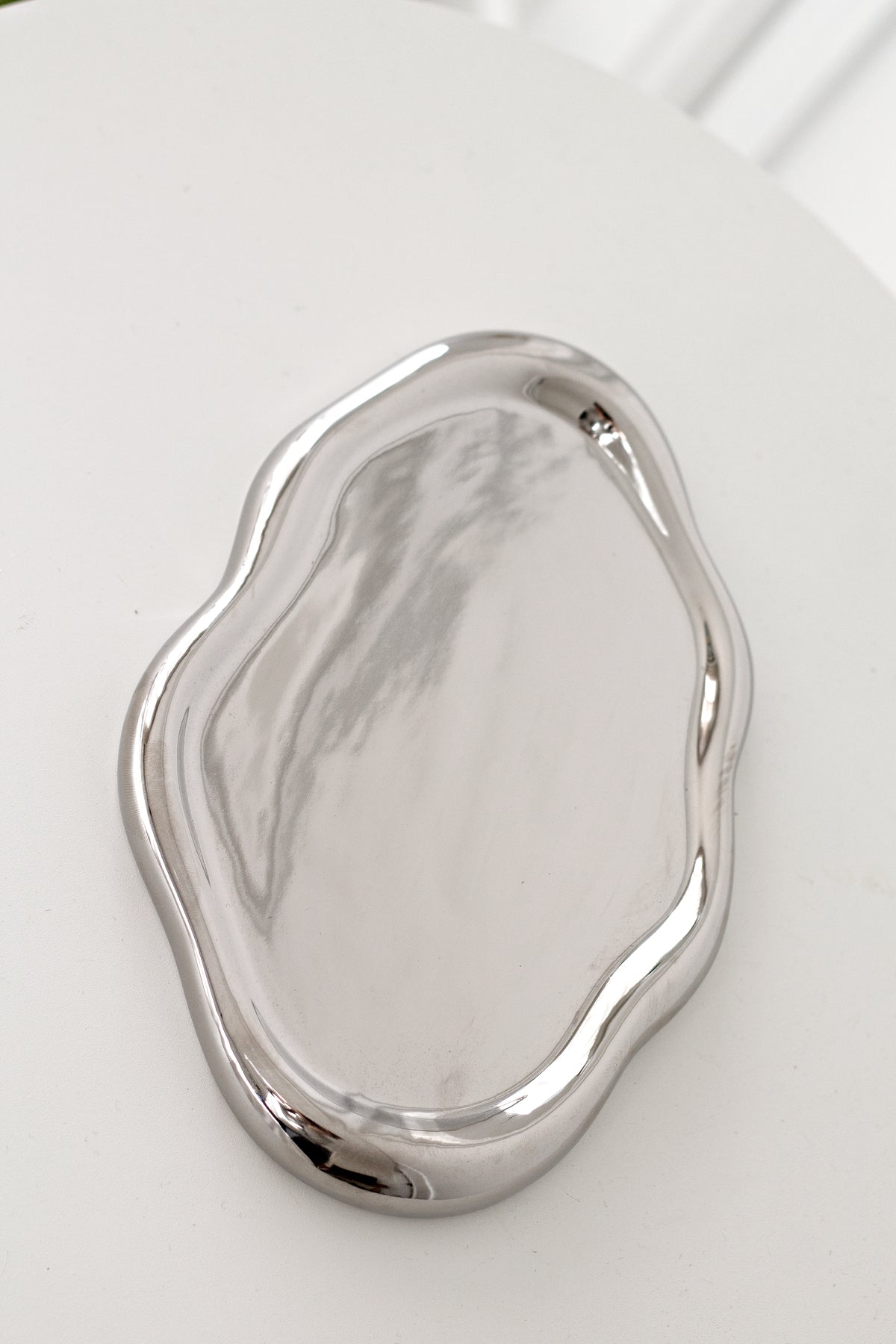 Empty silver electroplated cloud tray photographed from above on a white table