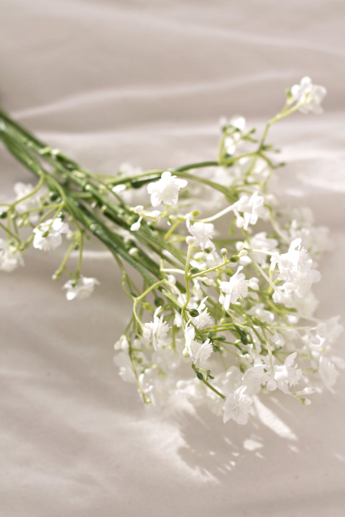 Faux gypsophila stems lying on soft linen