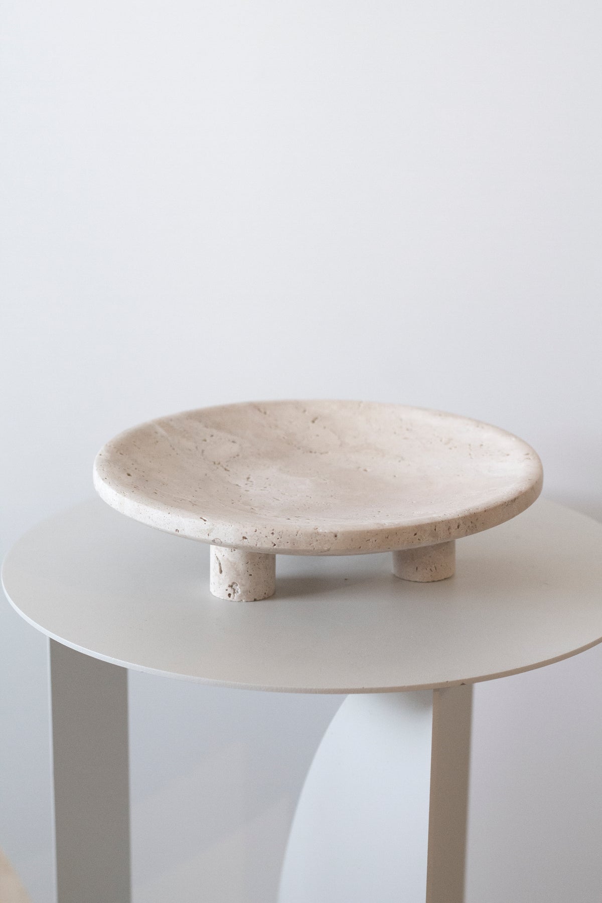 Nome stand in Light Travertine displayed on a white side table