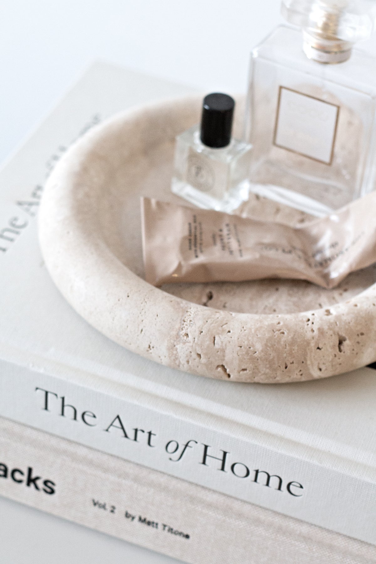 Bay round travertine tray styled on a console with vase and books