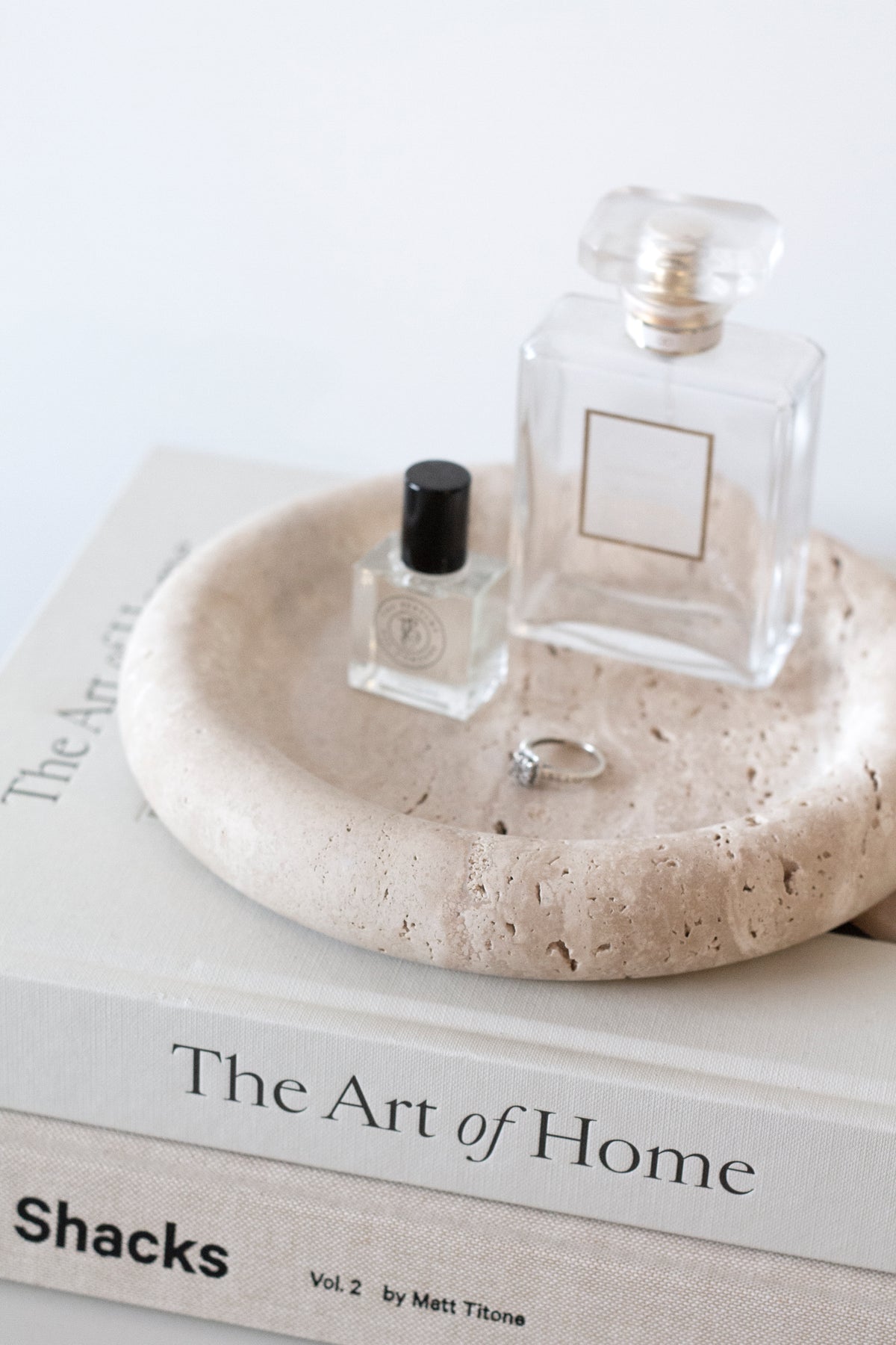 Bay Round Tray with two perfume bottles and a ring on stacked books, seen from the side