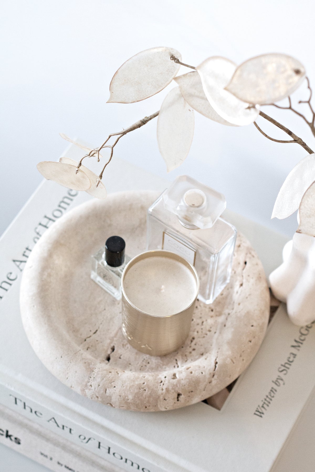 Bay Round Tray with perfume bottles and a candle on books beside dried honesty stems
