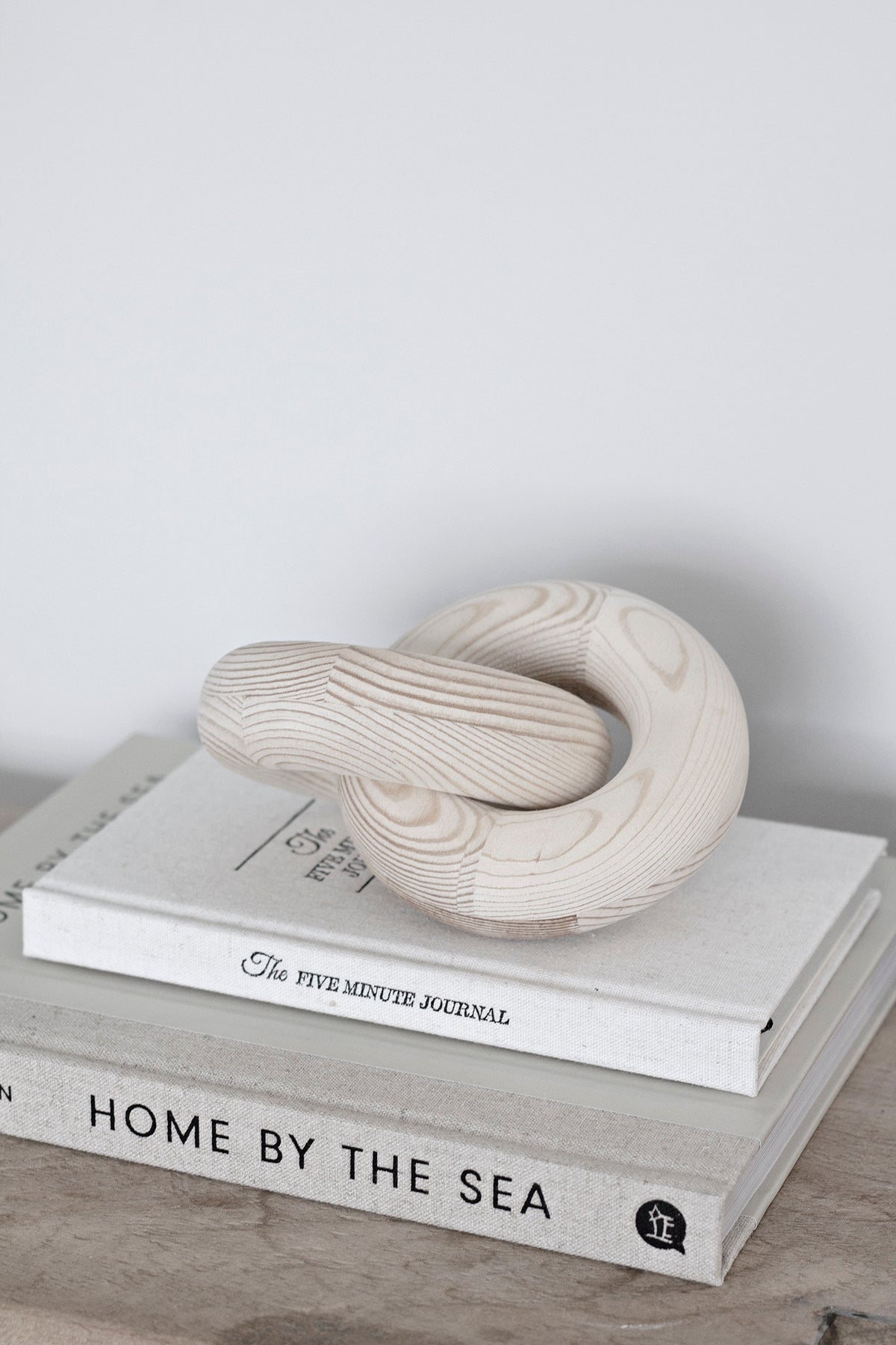 Natural wood knot sculpture on stacked books on a timber floor