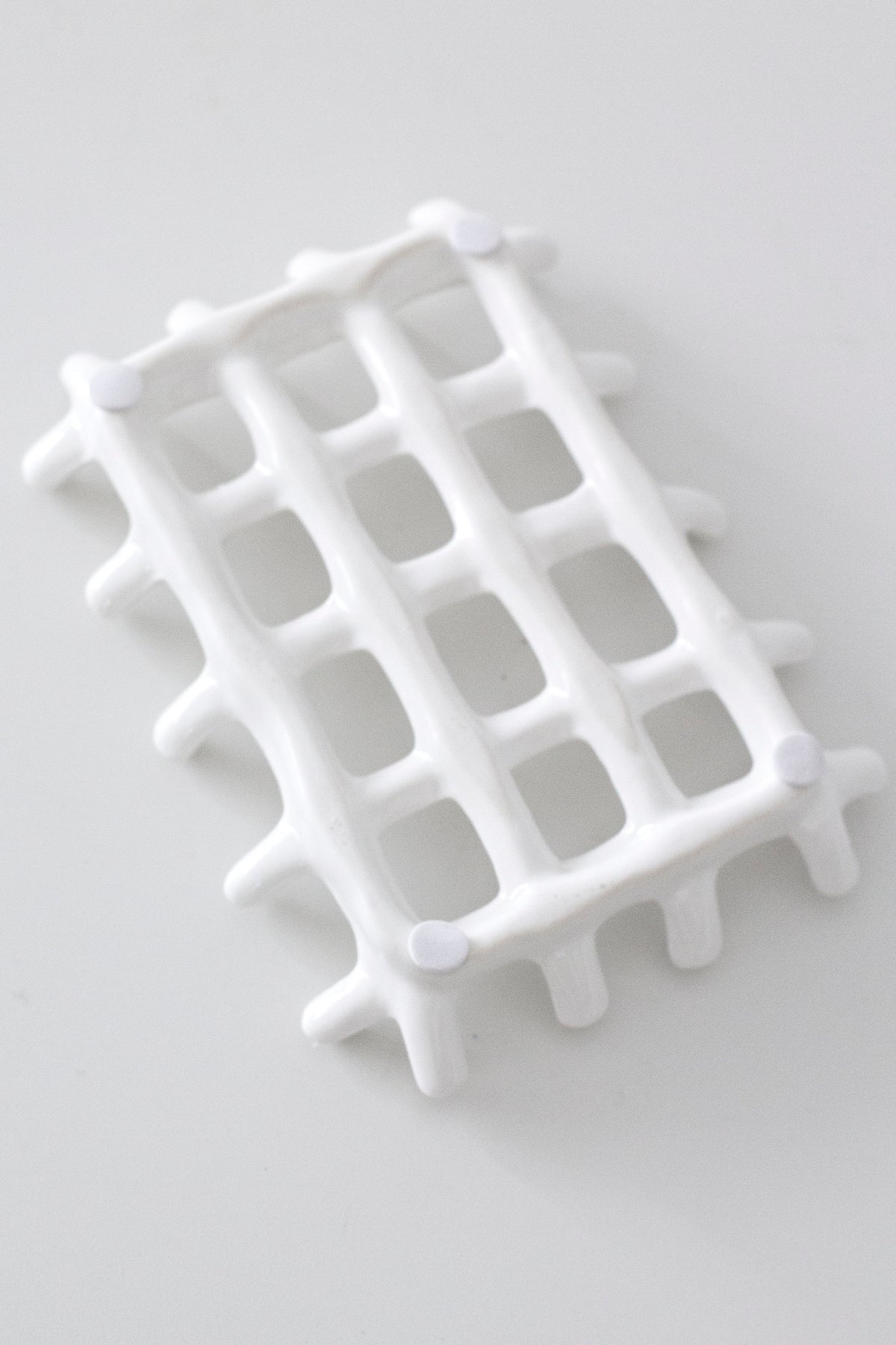 Edie soap dish seen from above on a pale surface, the open grid catching shadow