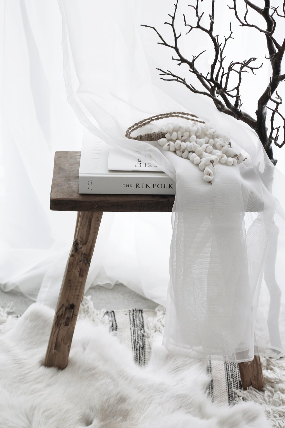 Small recycled teak bench styled with books, a beaded garland and a black branch