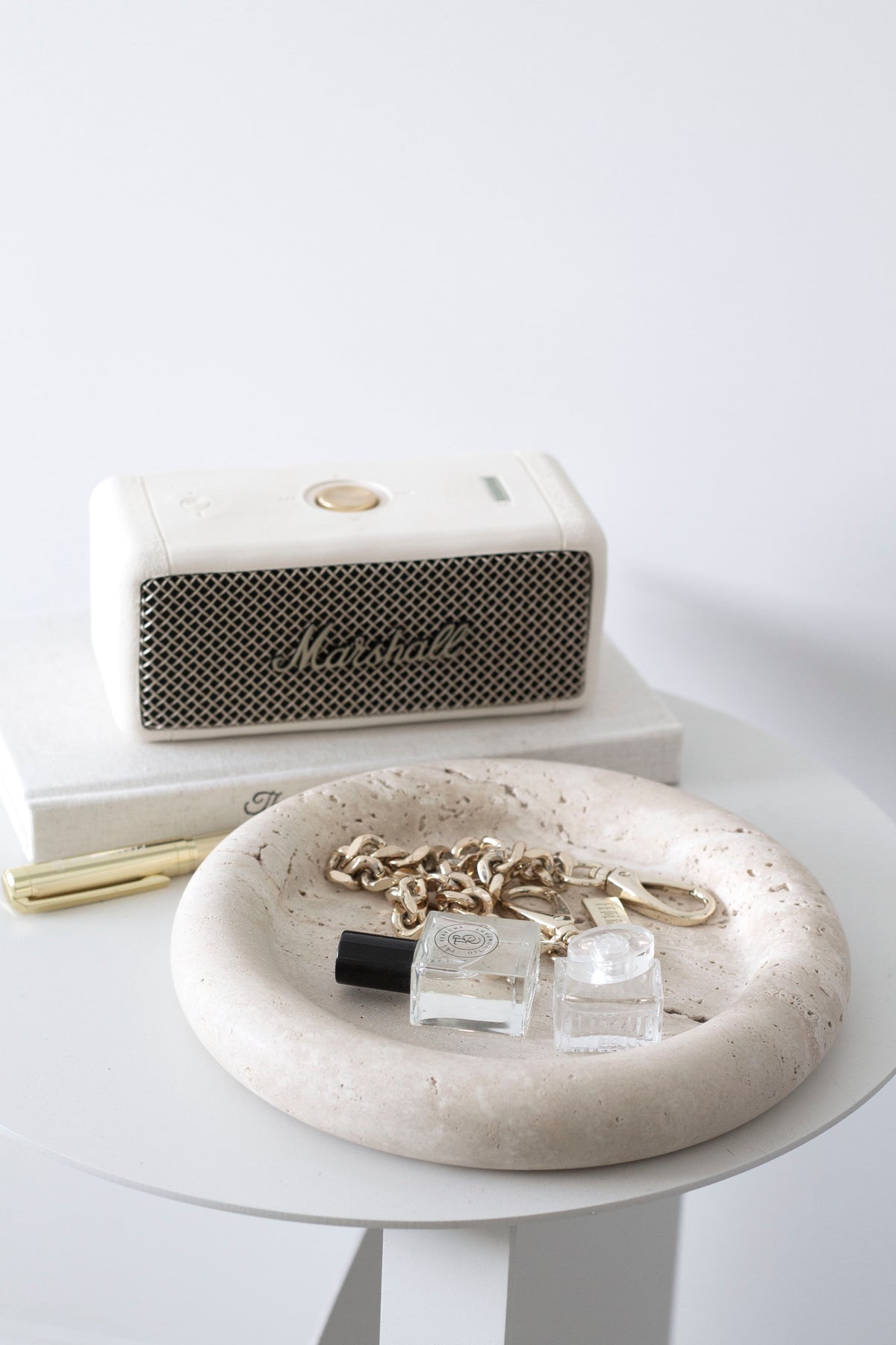 Bay Round Tray holding a gold chain and perfume oils beside a portable speaker on a white side table