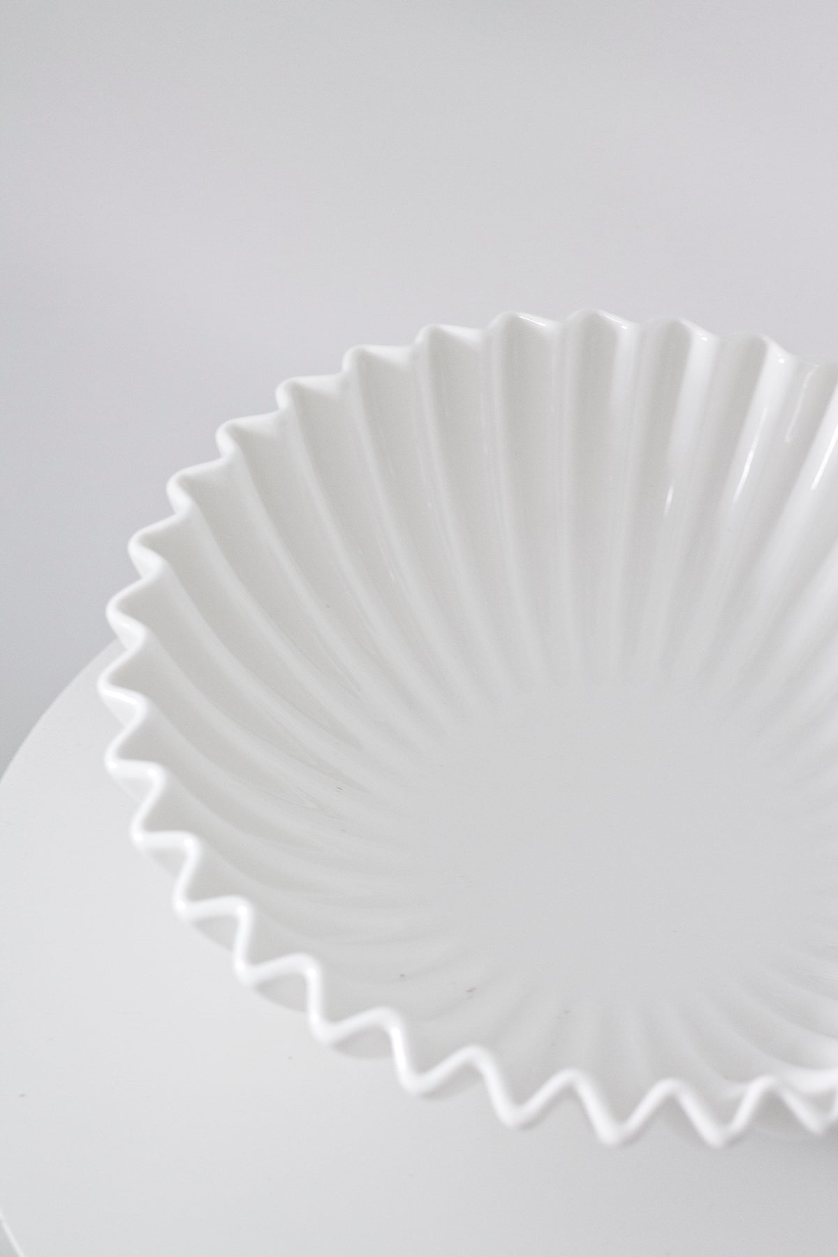 Close view of the glossy white fluted ceramic bowl showing its pleated, scalloped rim