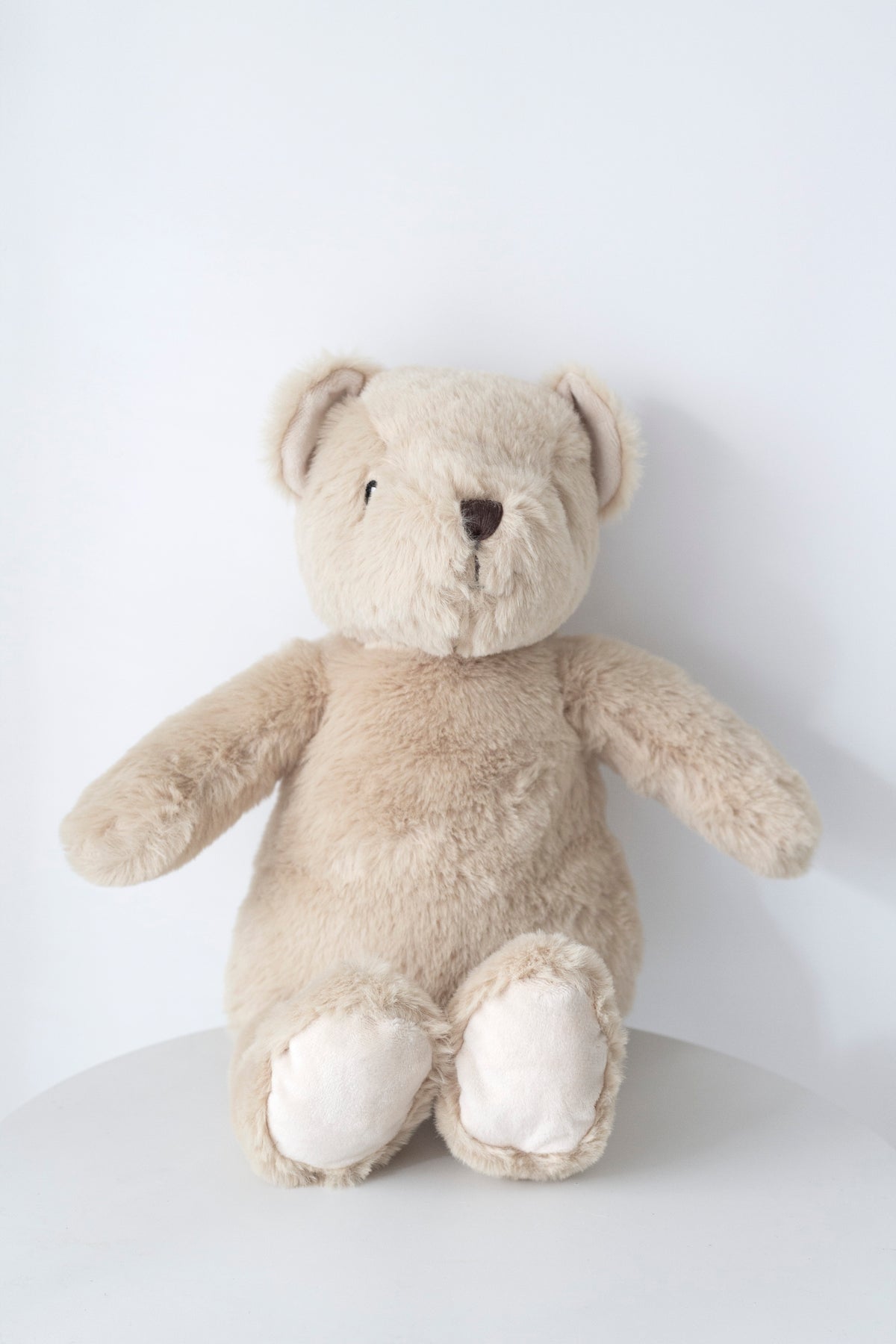 Fawn Flopsy Bear sitting on a white table against a pale grey wall