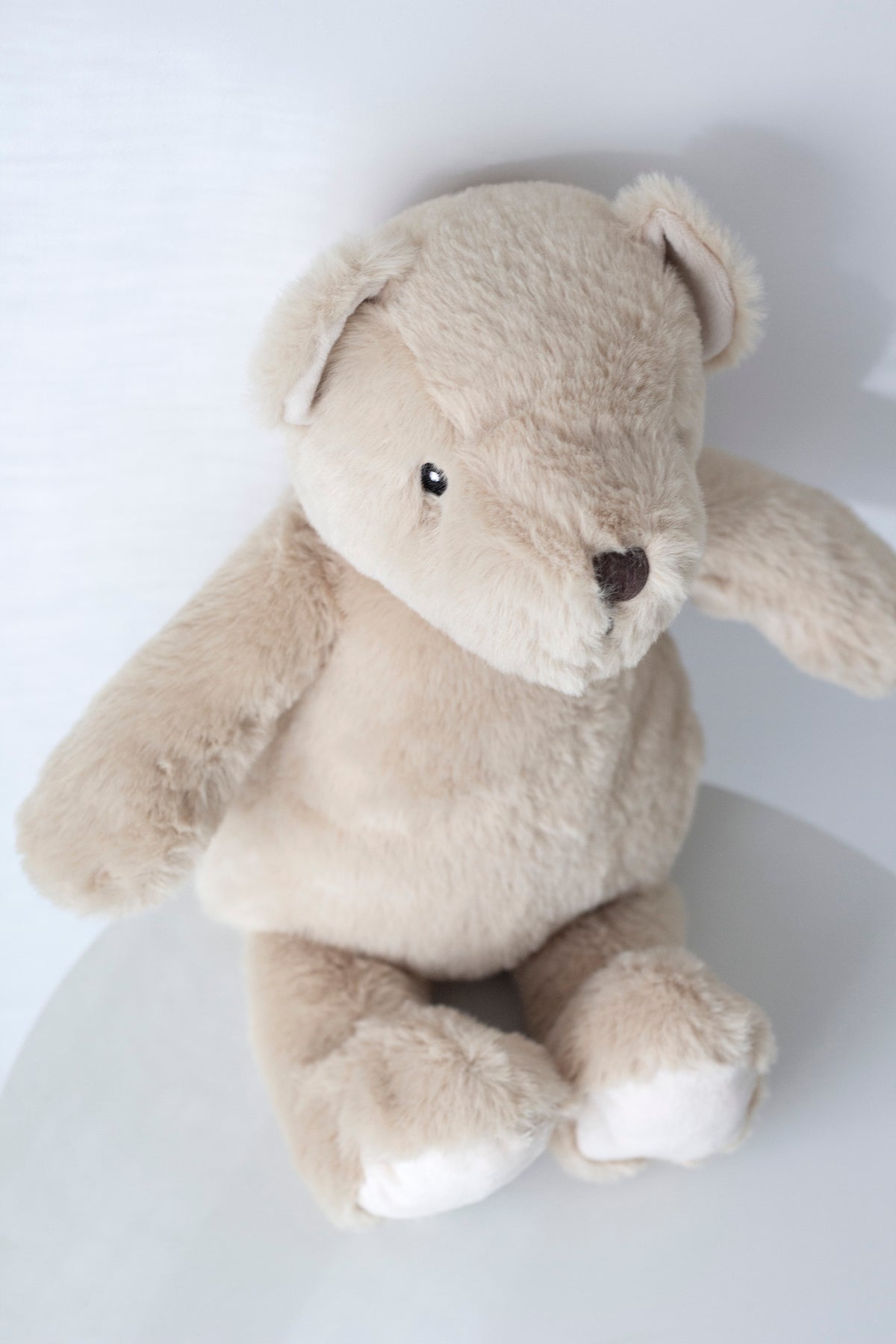 Close view of a Fawn Flopsy Bear sitting on a white table, angled
