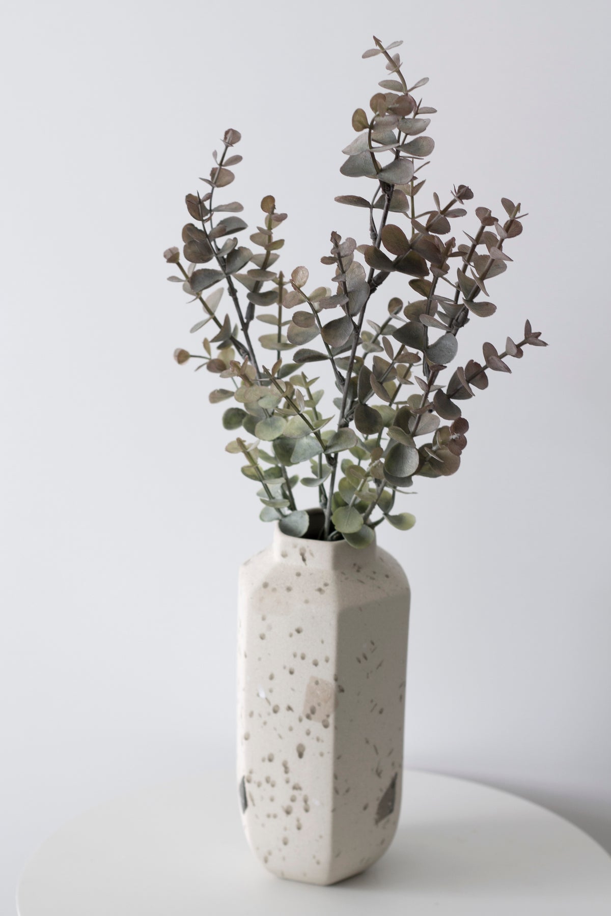 Faux eucalyptus in a speckled stone vase