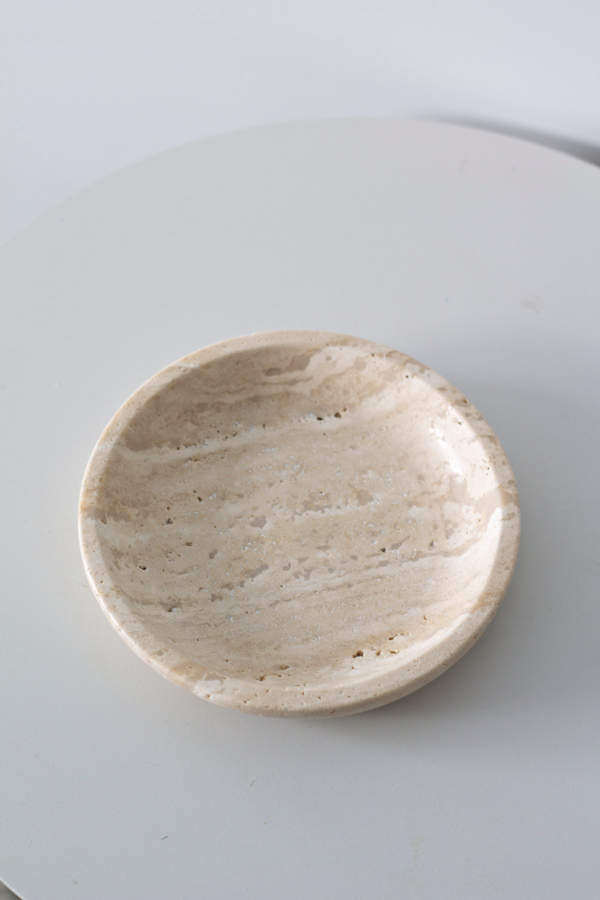 Travertine tray seen from above on a pale grey surface, stone banding visible