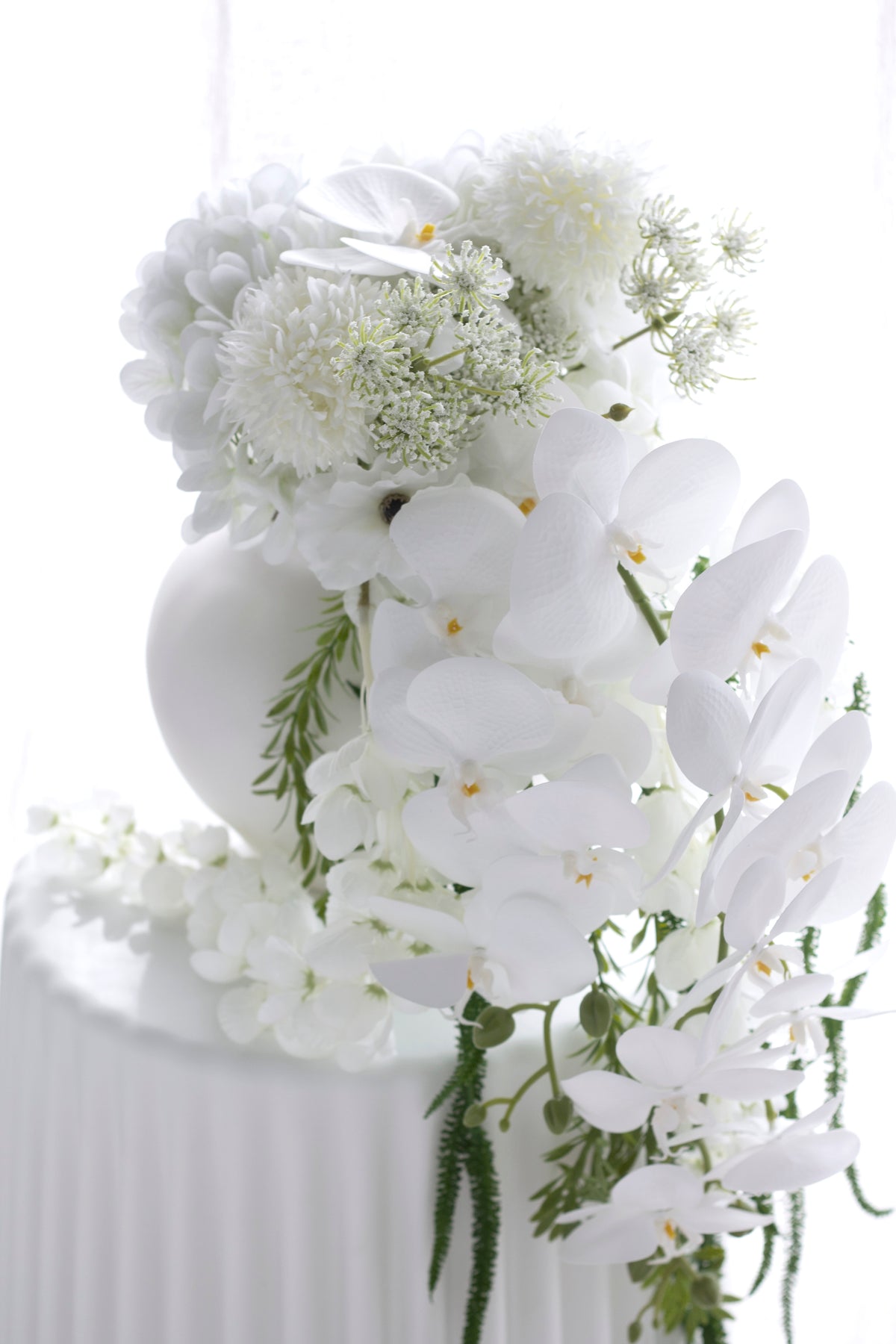 The bouquet in a ribbed white vase, orchid stems arching over the rim