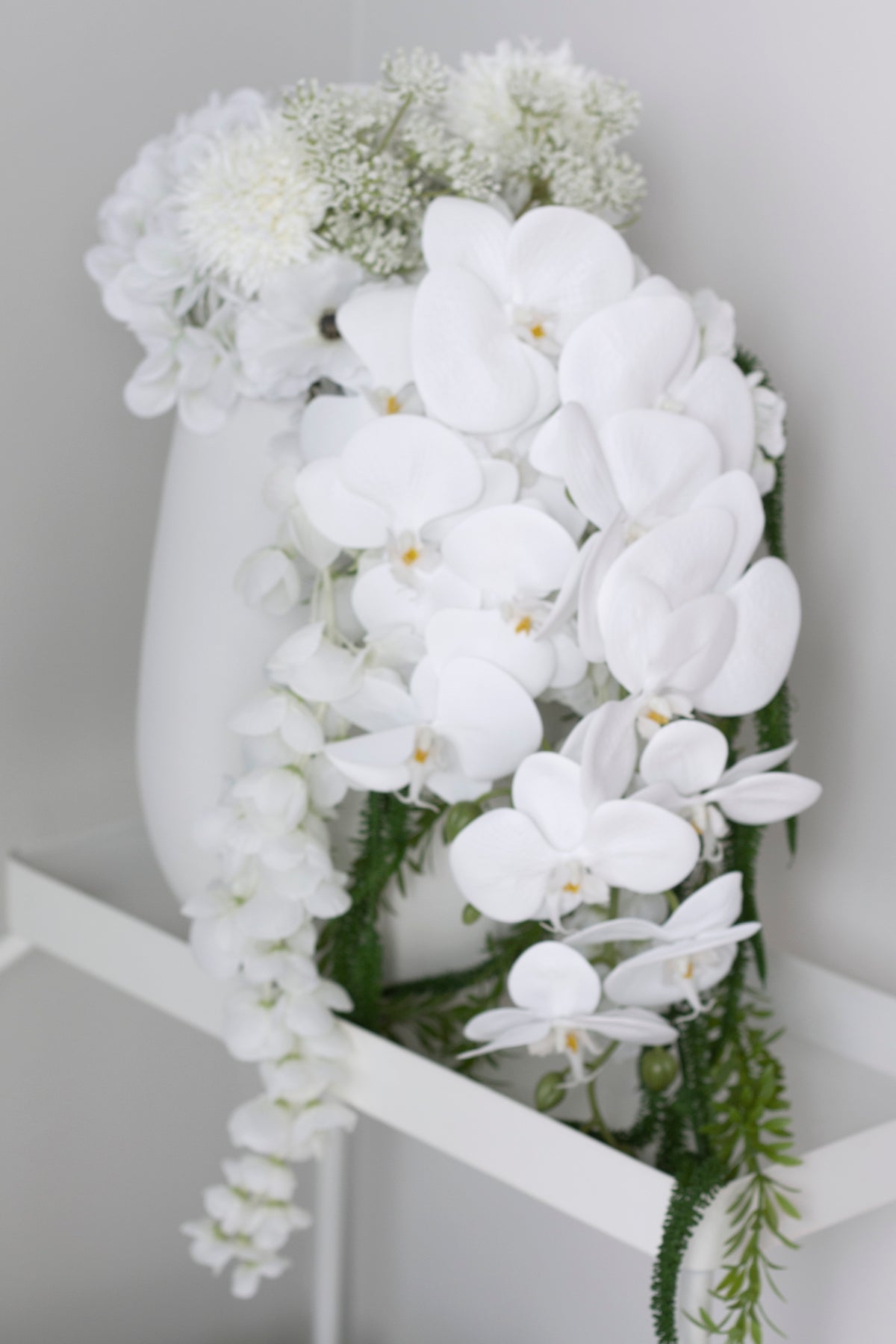 Bouquet in a white vase on a bench, trailing amaranthus hanging over the edge