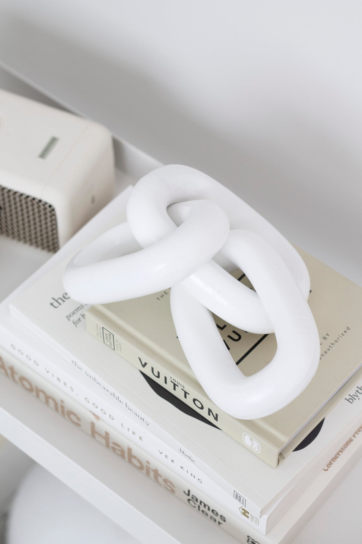 White wooden chain on stacked books beside a small fabric covered speaker