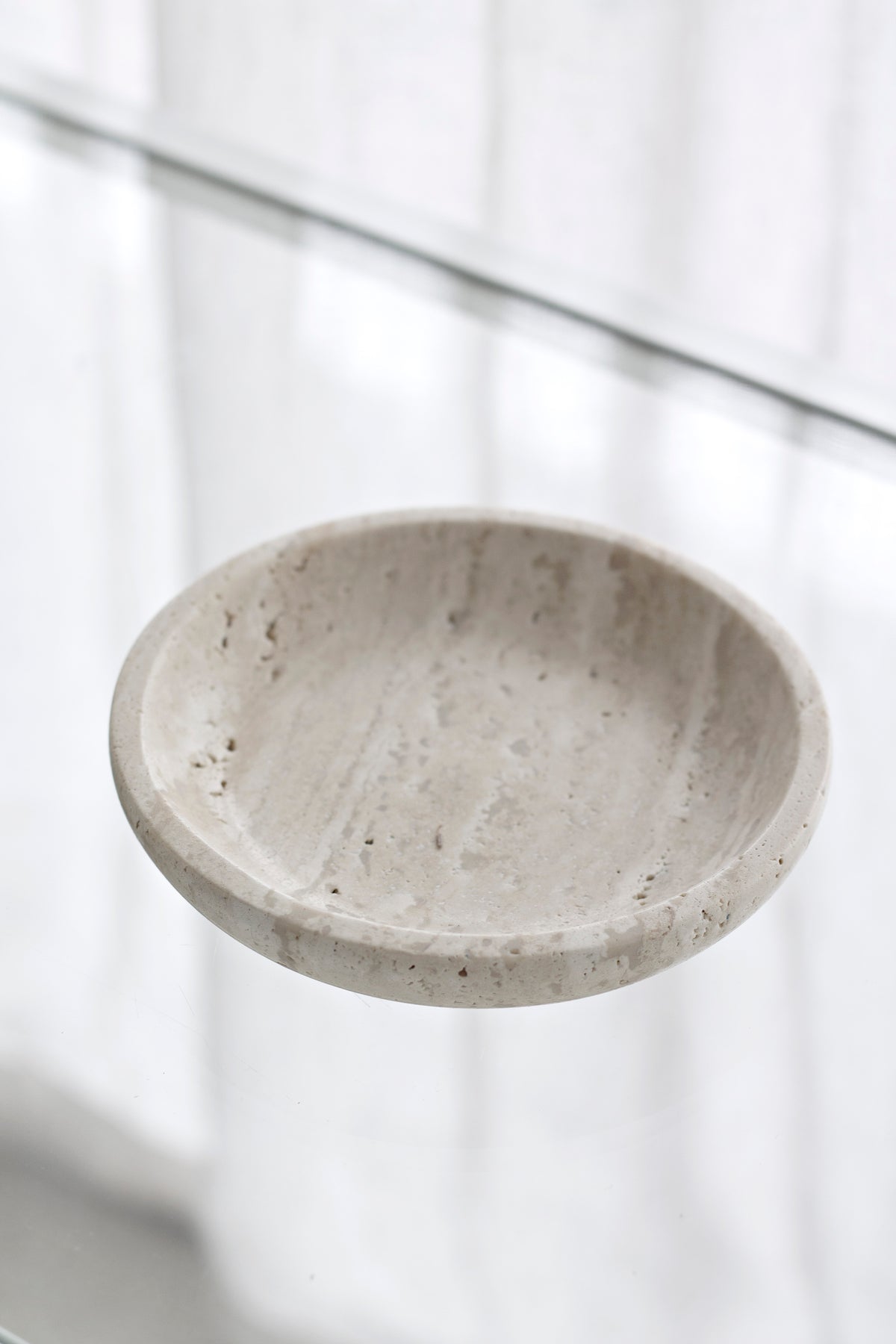 Travertine tray angled to show the shallow well and rounded rim