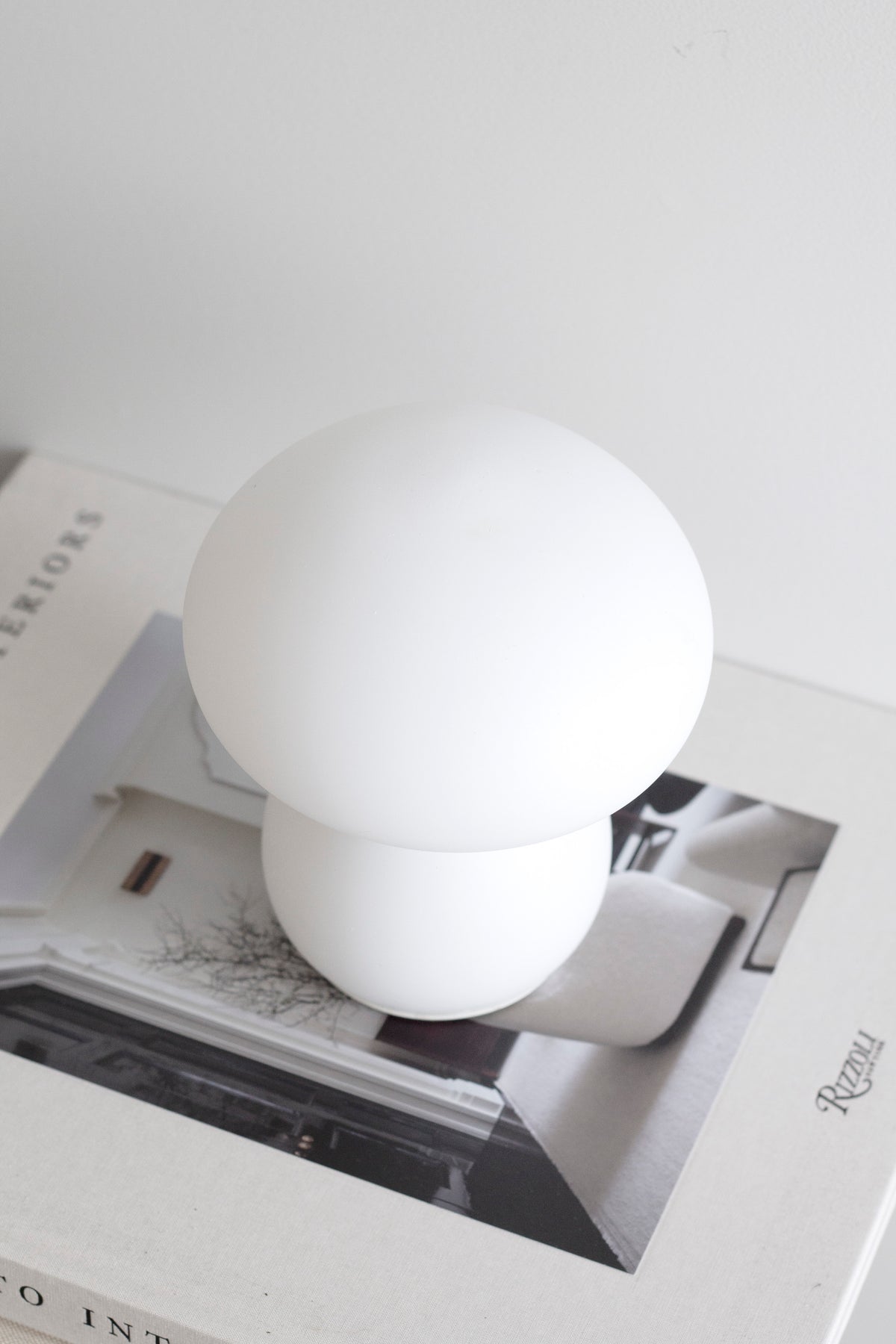 Mushroom lamp resting on an open magazine, curtain light behind