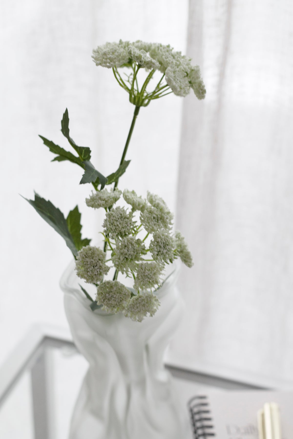 Queen Anne's Lace faux stem styled in a frosted twisted vase on a glass side table