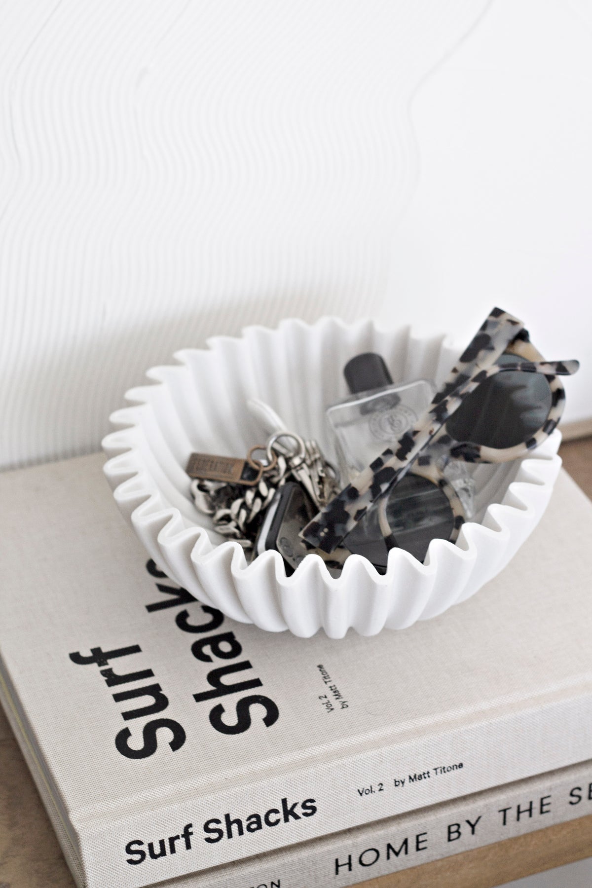 Surf Shacks Volume 2 under a white wavy bowl holding shells, on a book stack