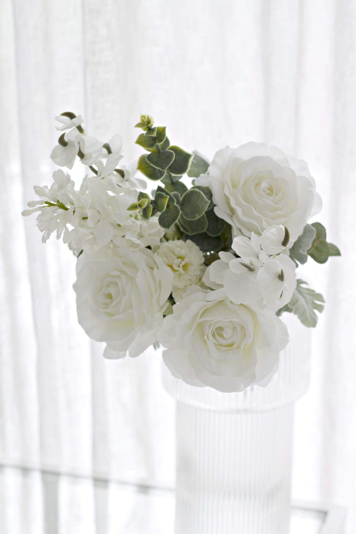 Close view of white faux roses and eucalyptus in the bouquet