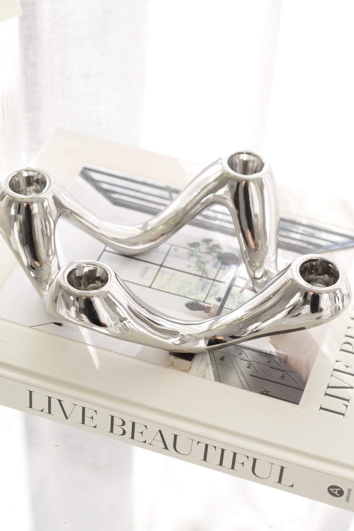 Silver candle holder angled on a large format book in bright window light
