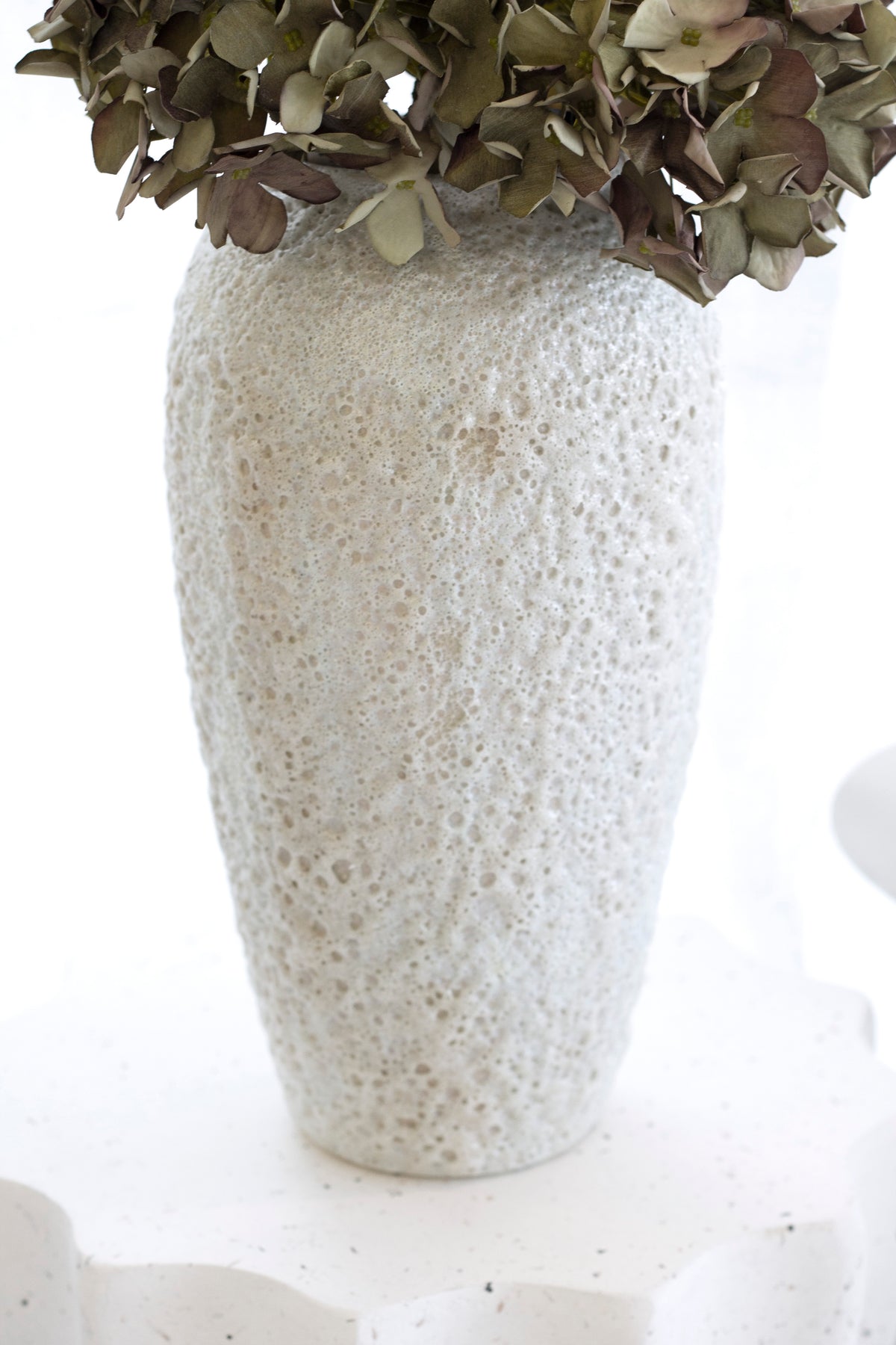 Close view of the tall Seafoam vase with dried hydrangea on a scalloped plinth