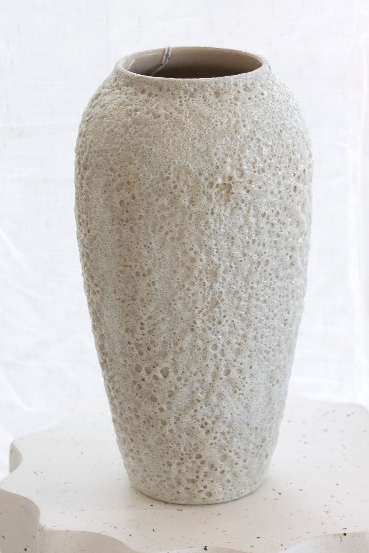 Tall Seafoam vase standing empty on a scalloped stone plinth