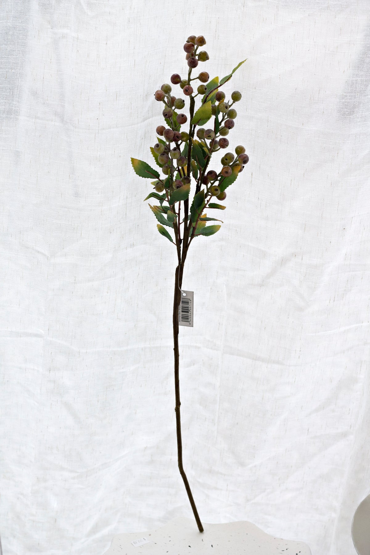 Full length view of the 66cm summer berry branch laid flat on white linen
