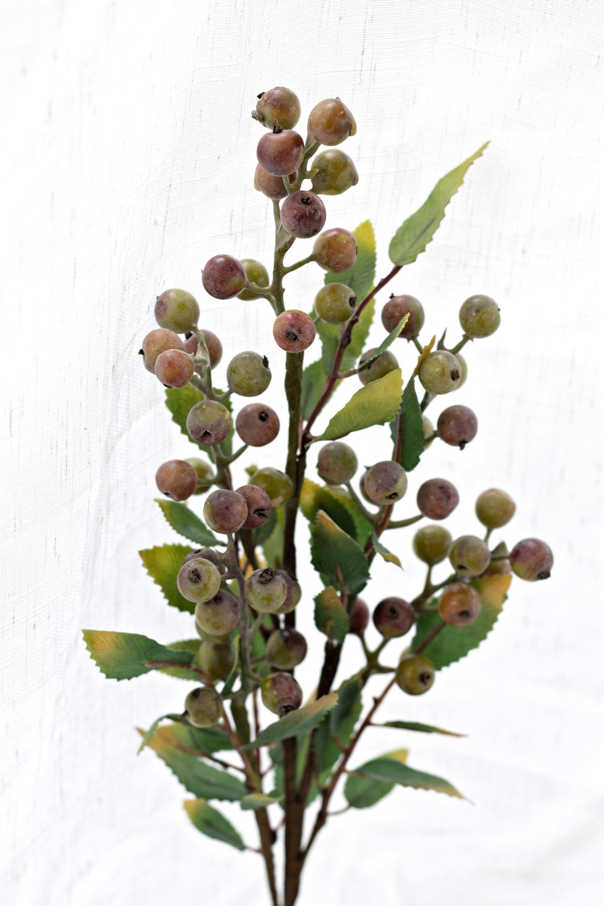 Close view of the faux berry clusters and green leaves on the summer berry branch