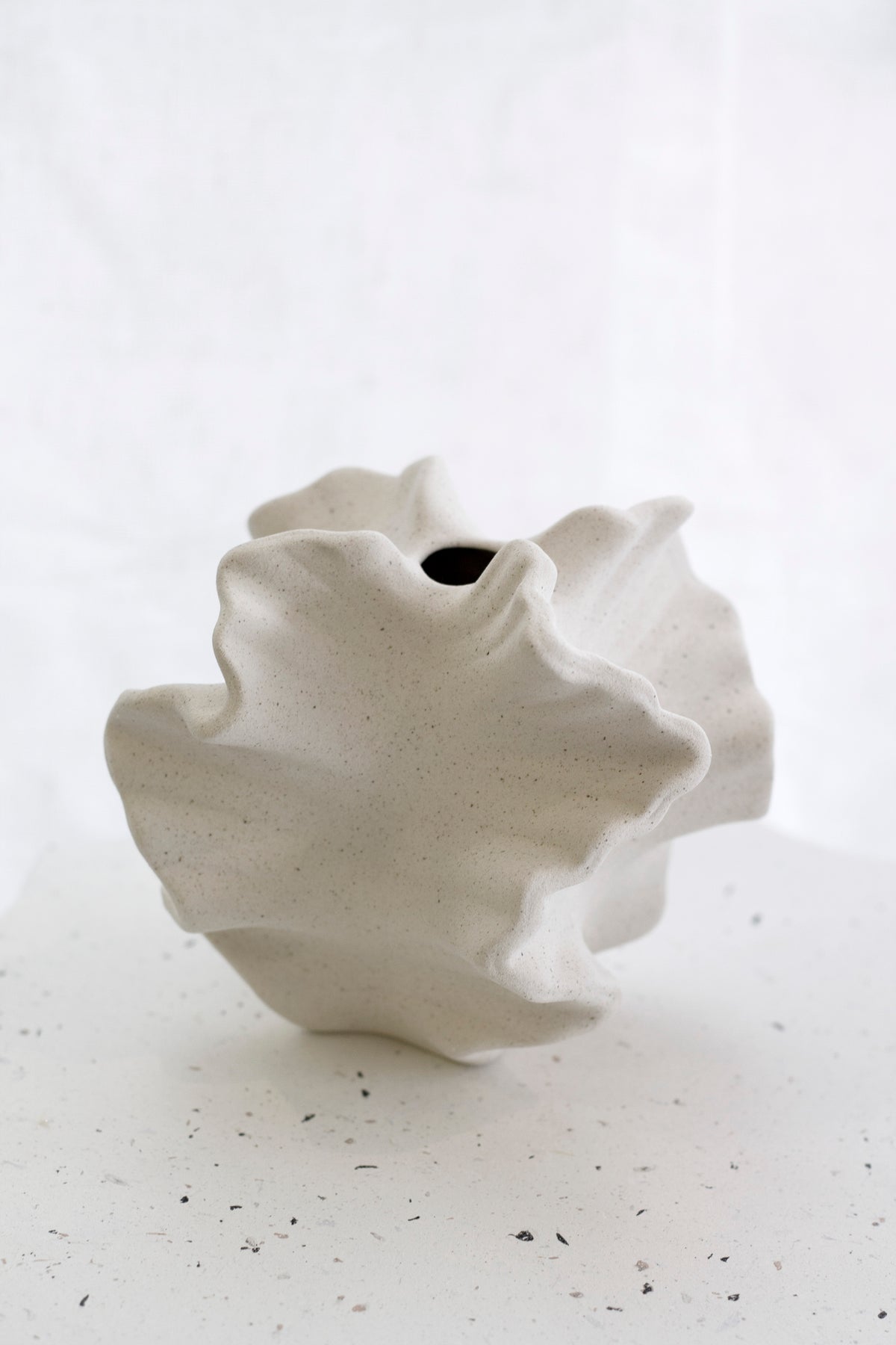 Coral vase on a speckled white surface, the small dark opening at the top