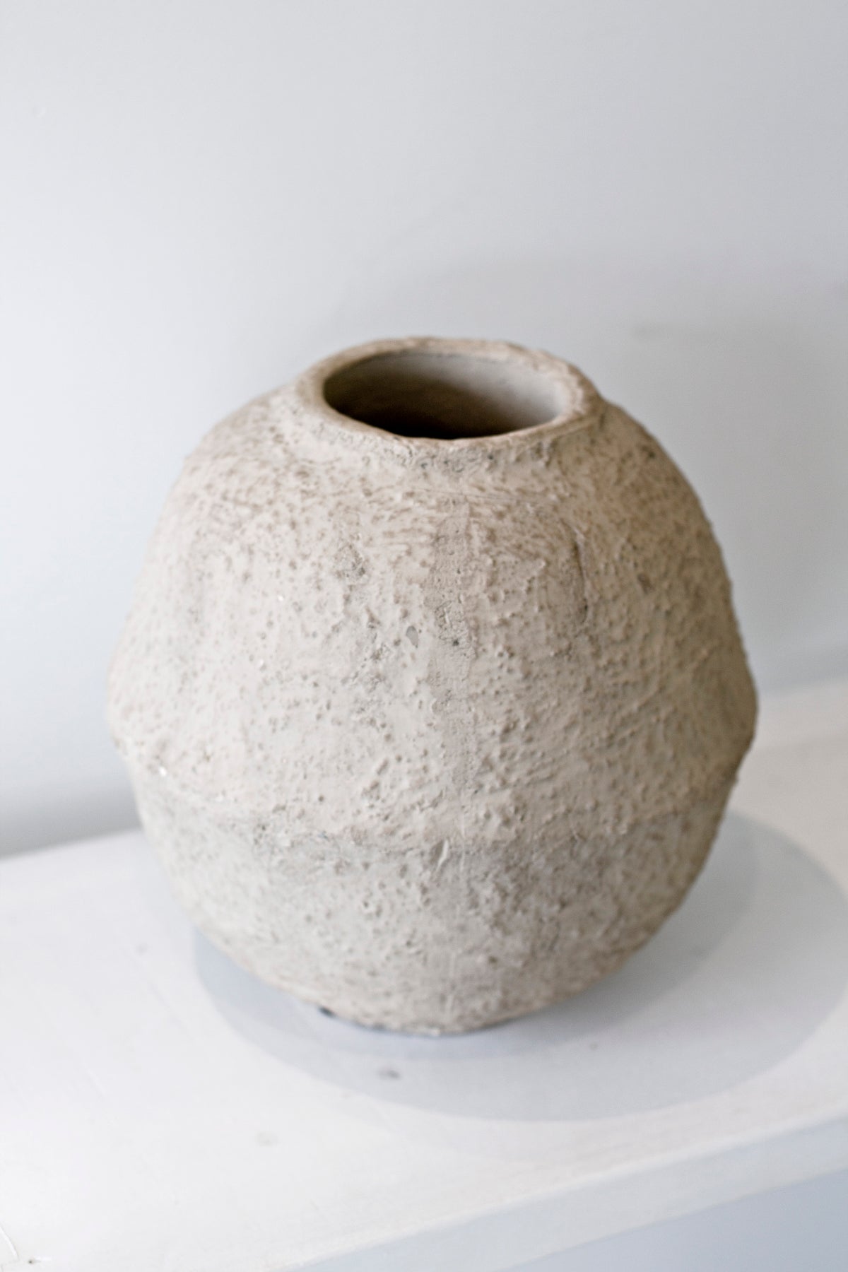 Close view of the Joni vase on a white plinth, showing the rough unglazed surface