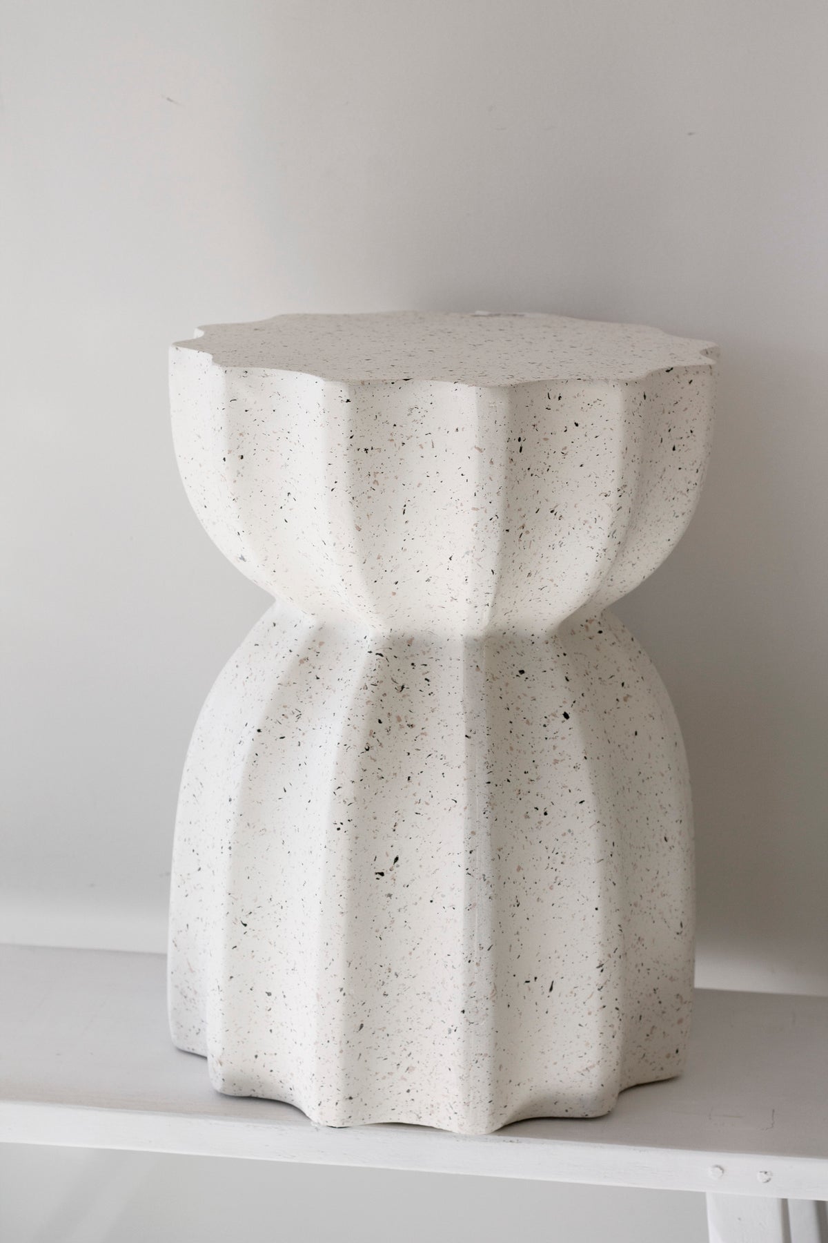 Fleck white fluted table from a low angle, speckles catching the daylight