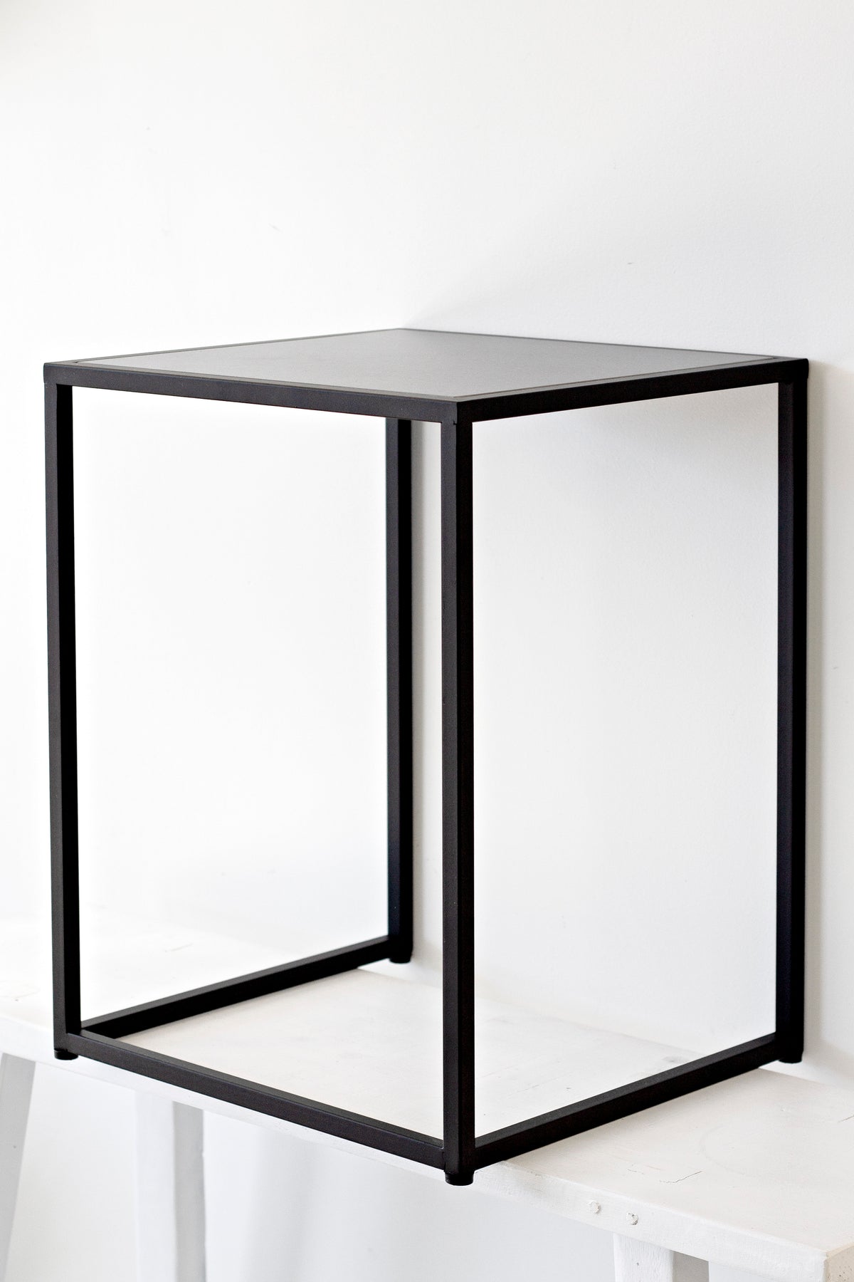 Angled view of the Sara side table, square profile with the dark top panel set into the frame
