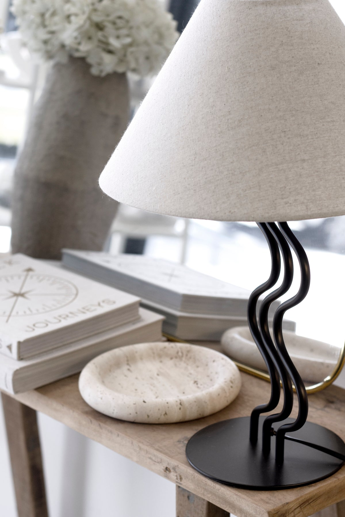 Close view of the Surge table lamp with a round tray and vase