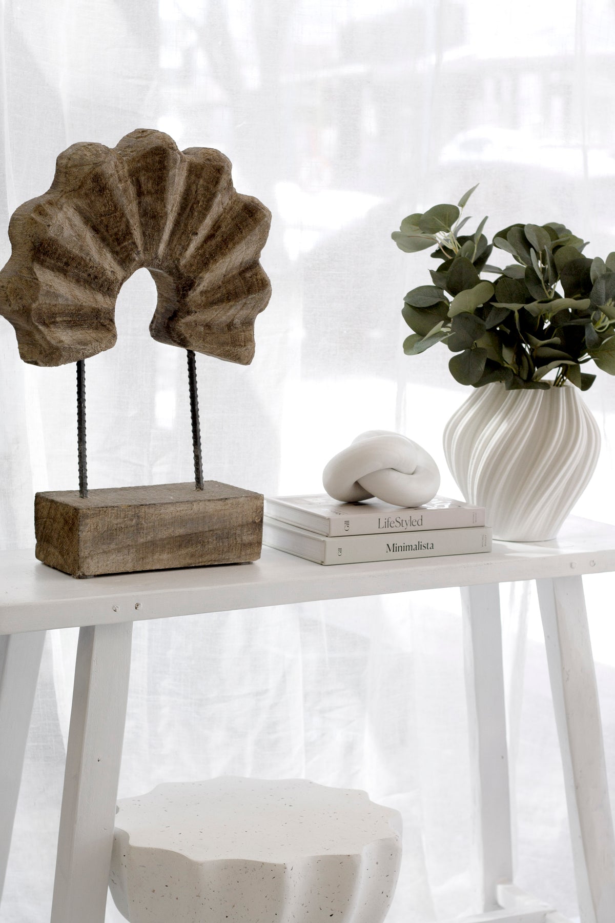 Small white Amelie fluted vase with green foliage on a console beside a shell sculpture