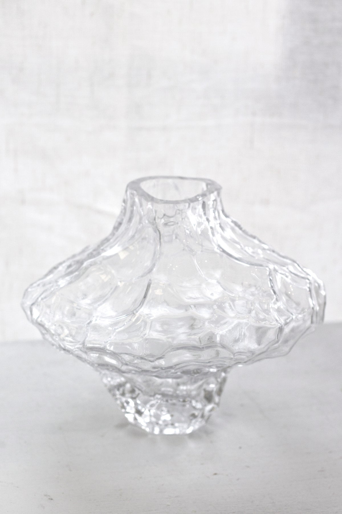Clear rippled crystal glass vase on a pale bench, showing the wide flared opening