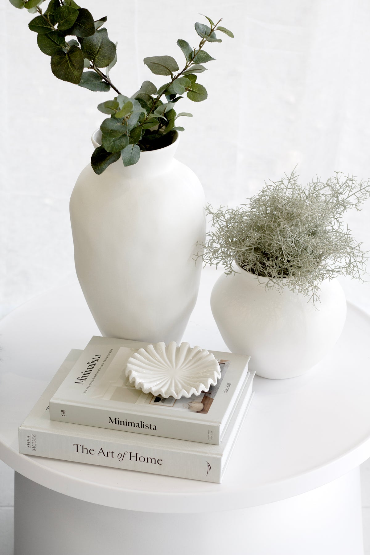 Bedside with white vases of greenery and the small white ruffle tray