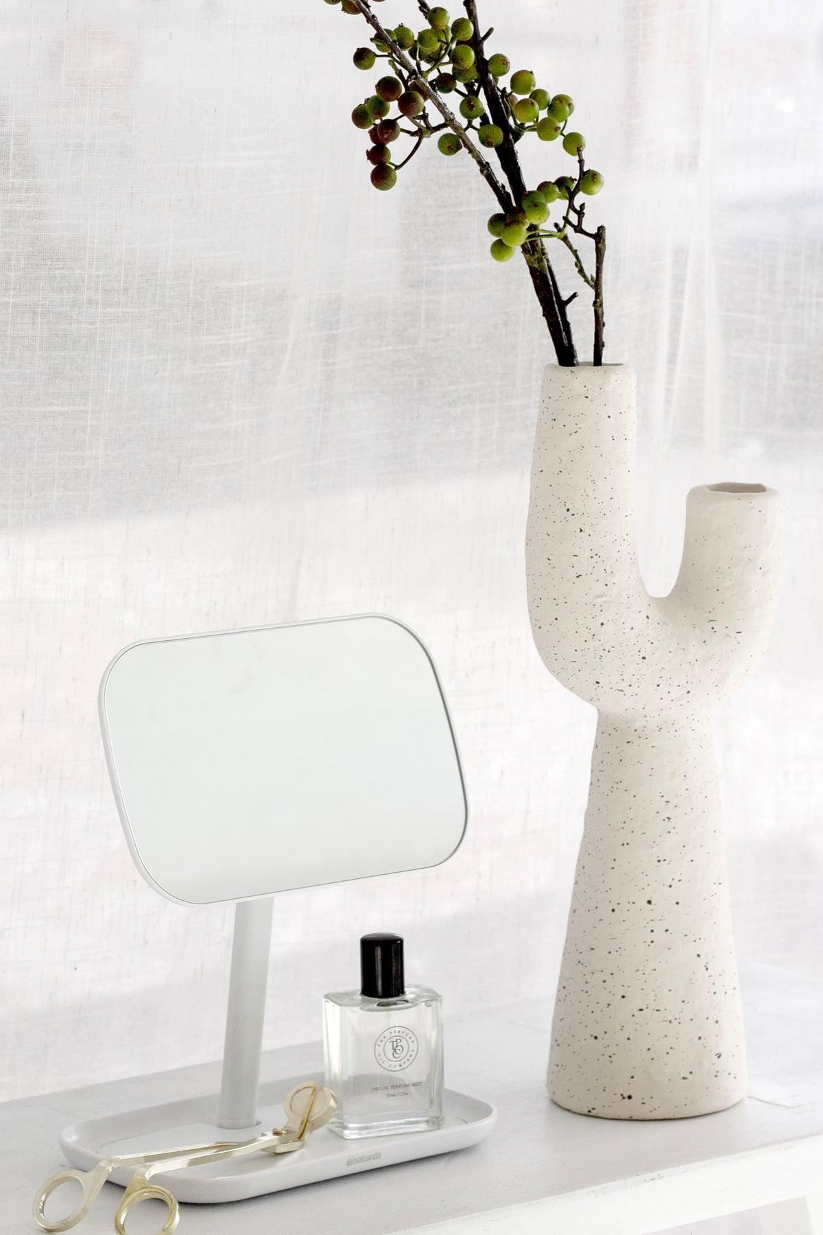 Close view of the Franki vase with berry stems beside a small mirror