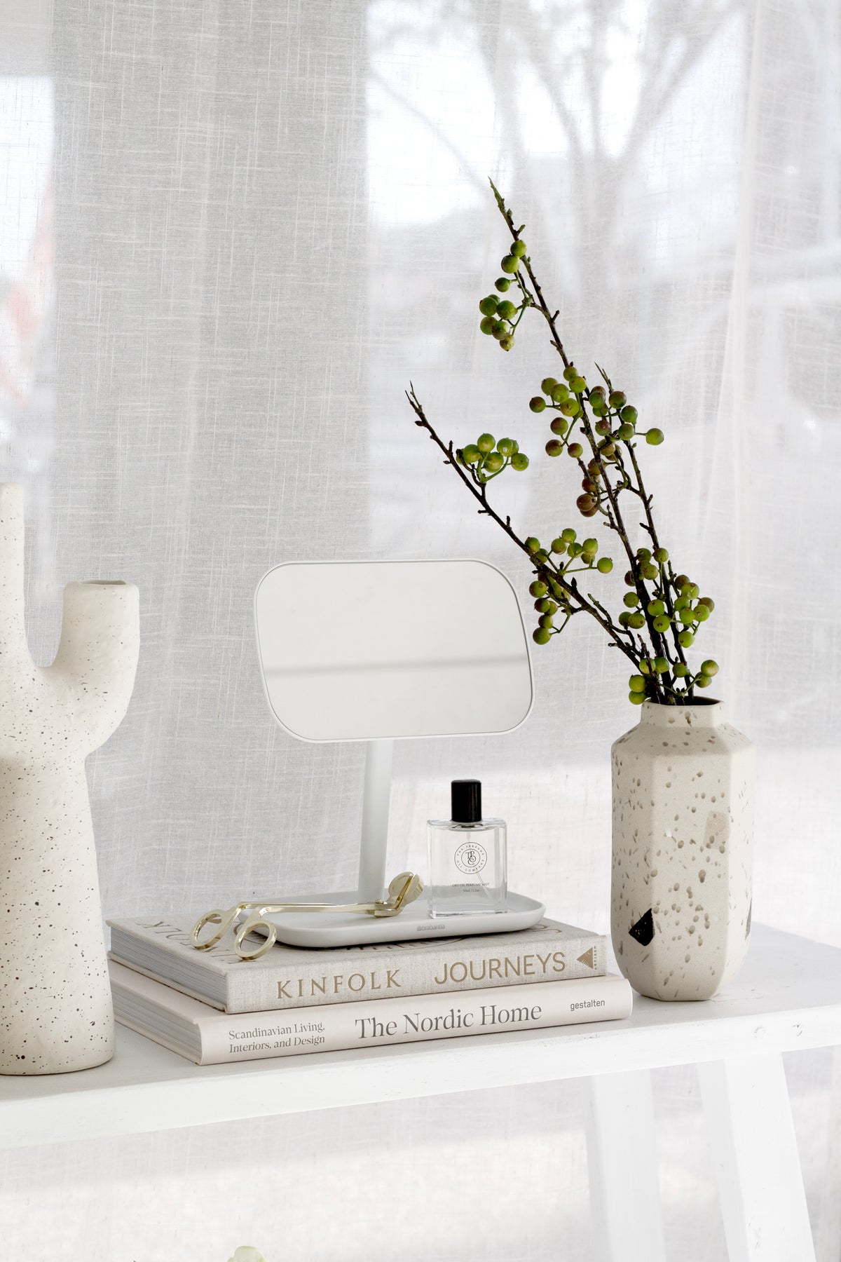 Franki vase on a white console with a mirror, a branch in a vase and white flowers