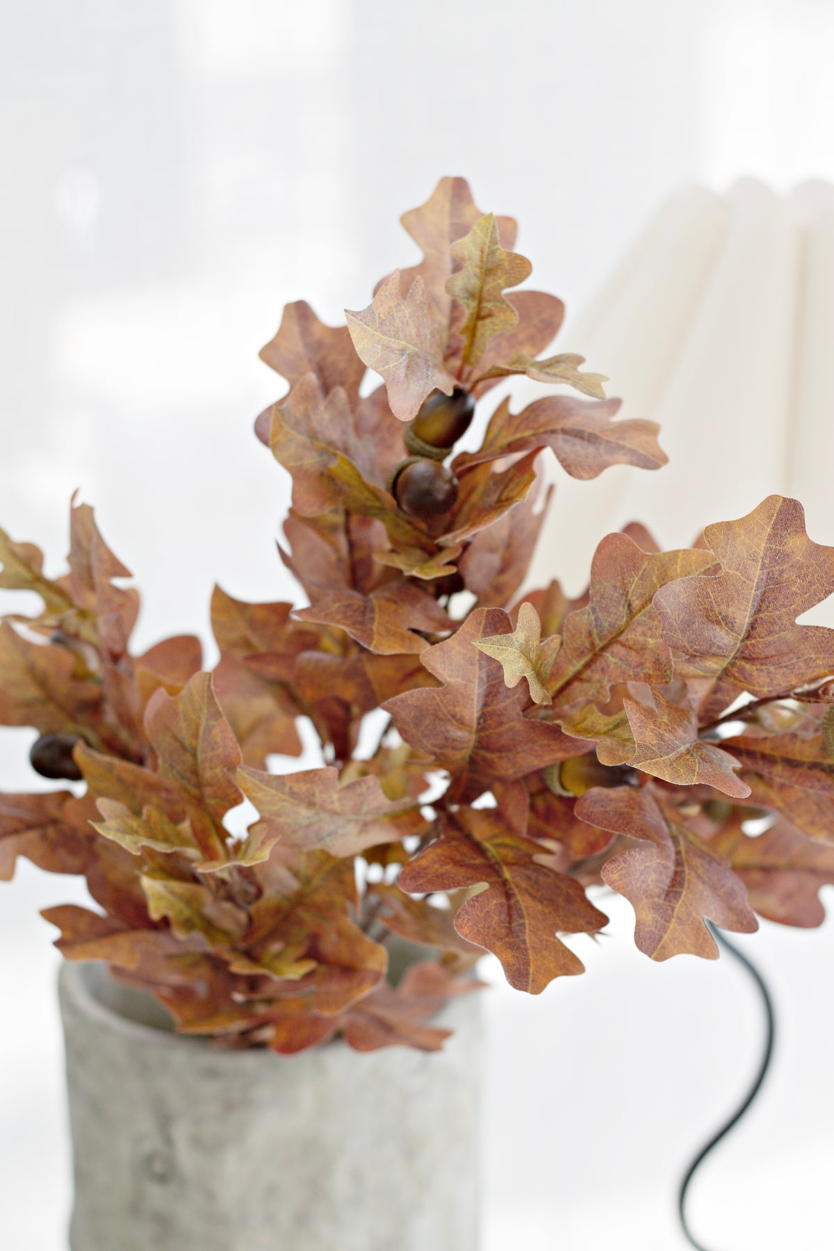 Close view of russet faux oak leaves in a textured grey vase