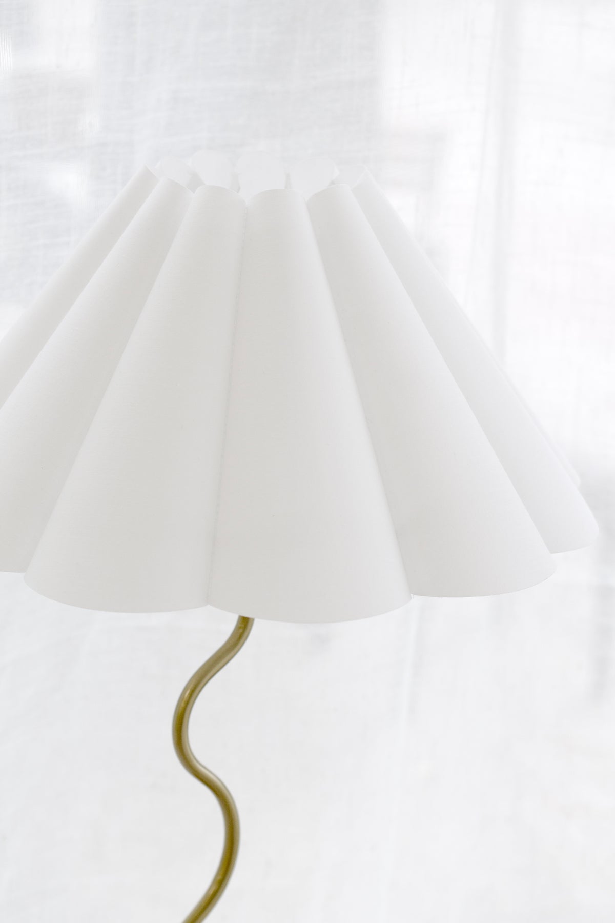 Brass zig-zag stem and fluted shade of the Wavy table lamp against a sheer curtain