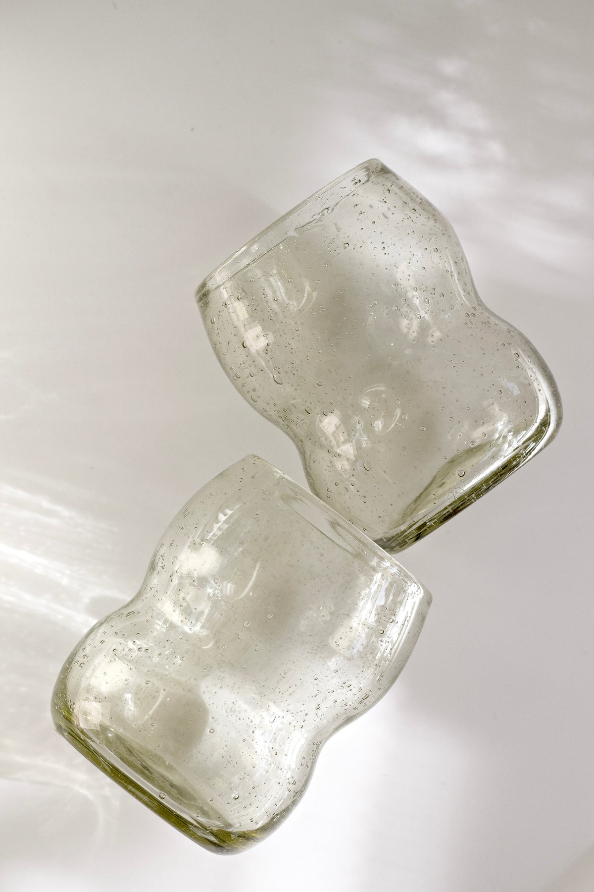 Two light amber Como tumblers lying on white in bright sunlight