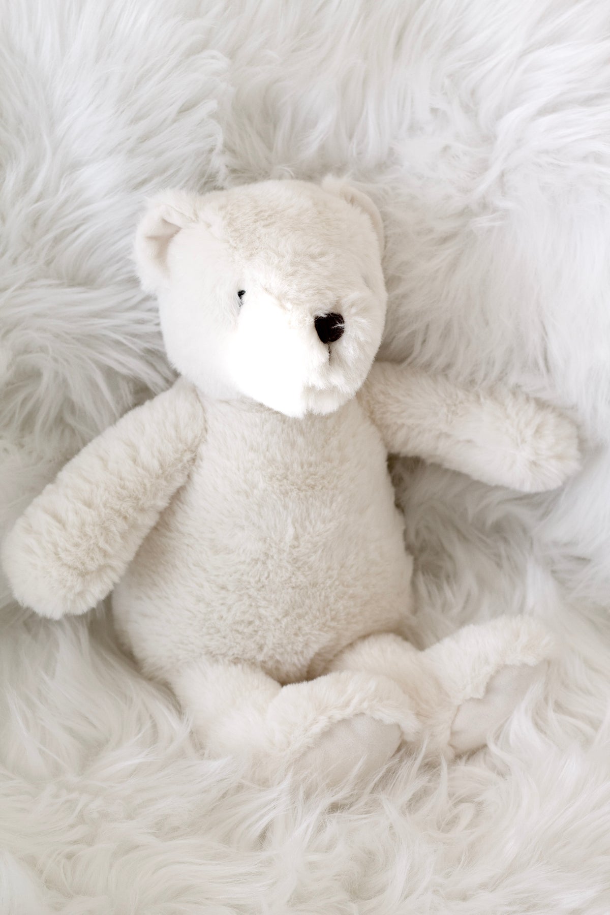 Warm White Flopsy Bear lying on white sheepskin