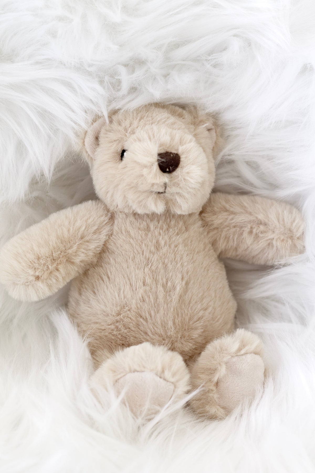 Fawn Flopsy Bear sitting on white sheepskin, front view
