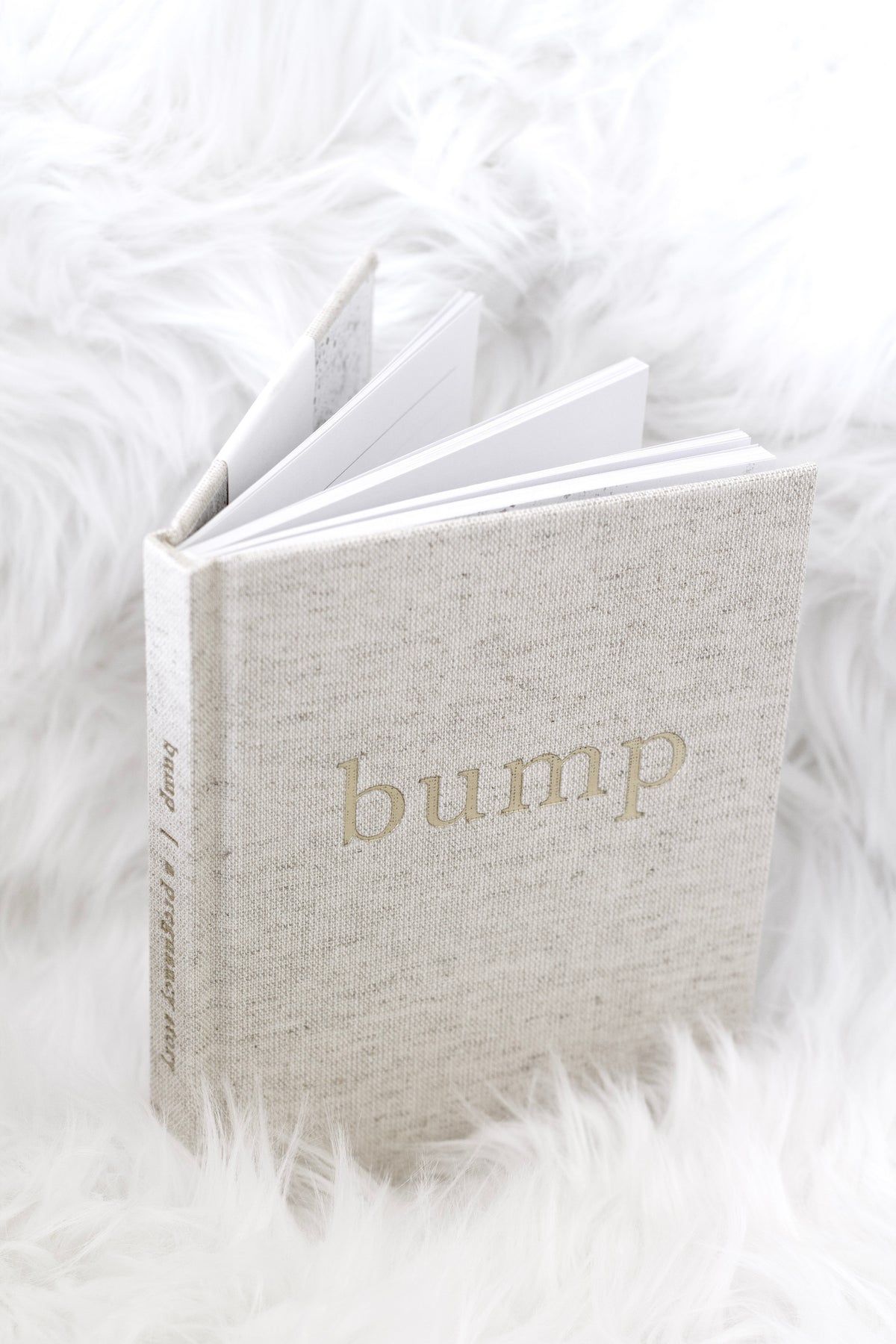Bump pregnancy journal standing partly open on white faux fur