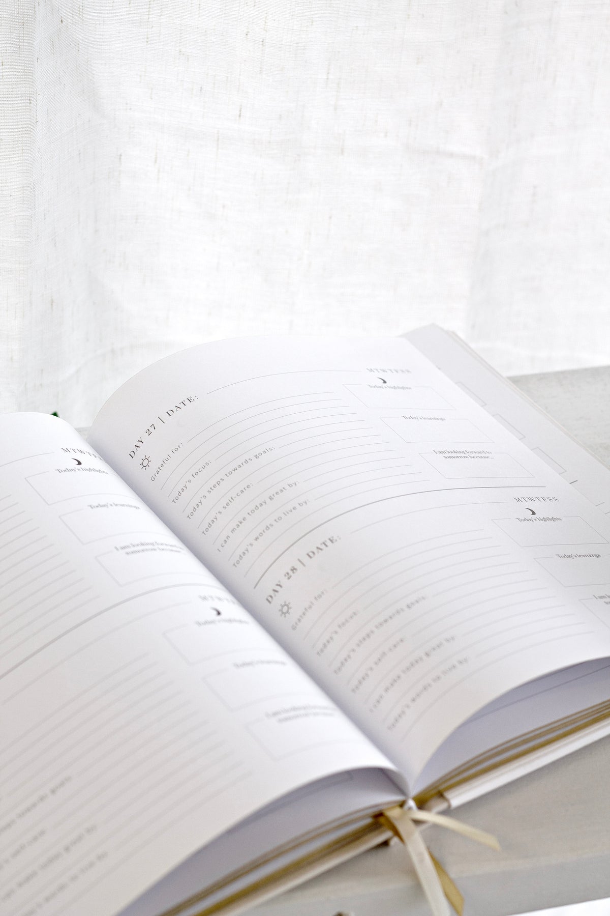 The YOU. journal lying open with its ribbon marker, showing ruled daily planning pages